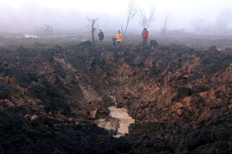 Locals gather around a shelling crater after a rocket hit the Pisochyn neighborhood outside Kharkiv, Ukraine, on March 9. 