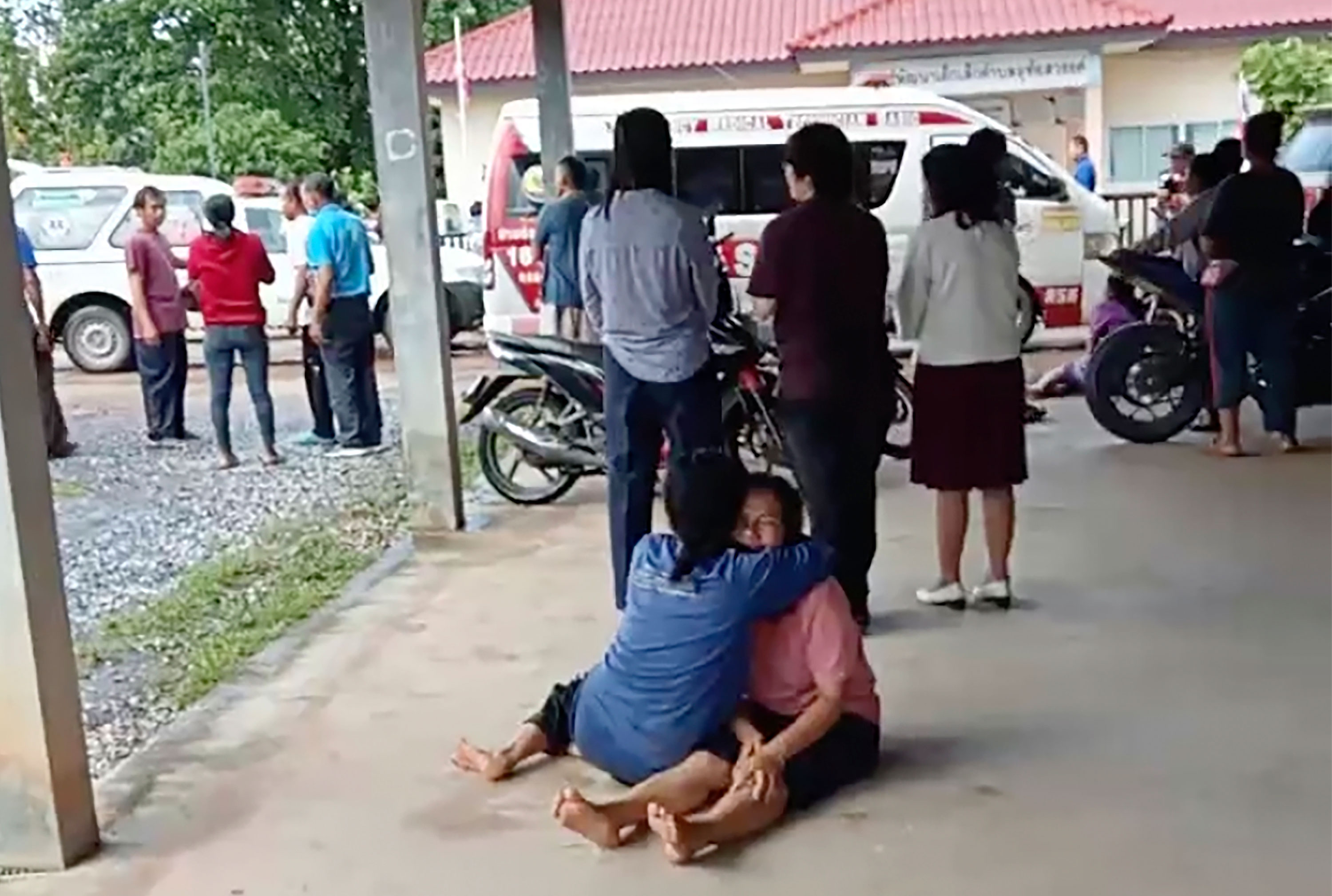 In this image taken from video, a woman is embraced outside the site of an attack at a daycare center in Nongbua Lamphu, Thailand, on Thursday.