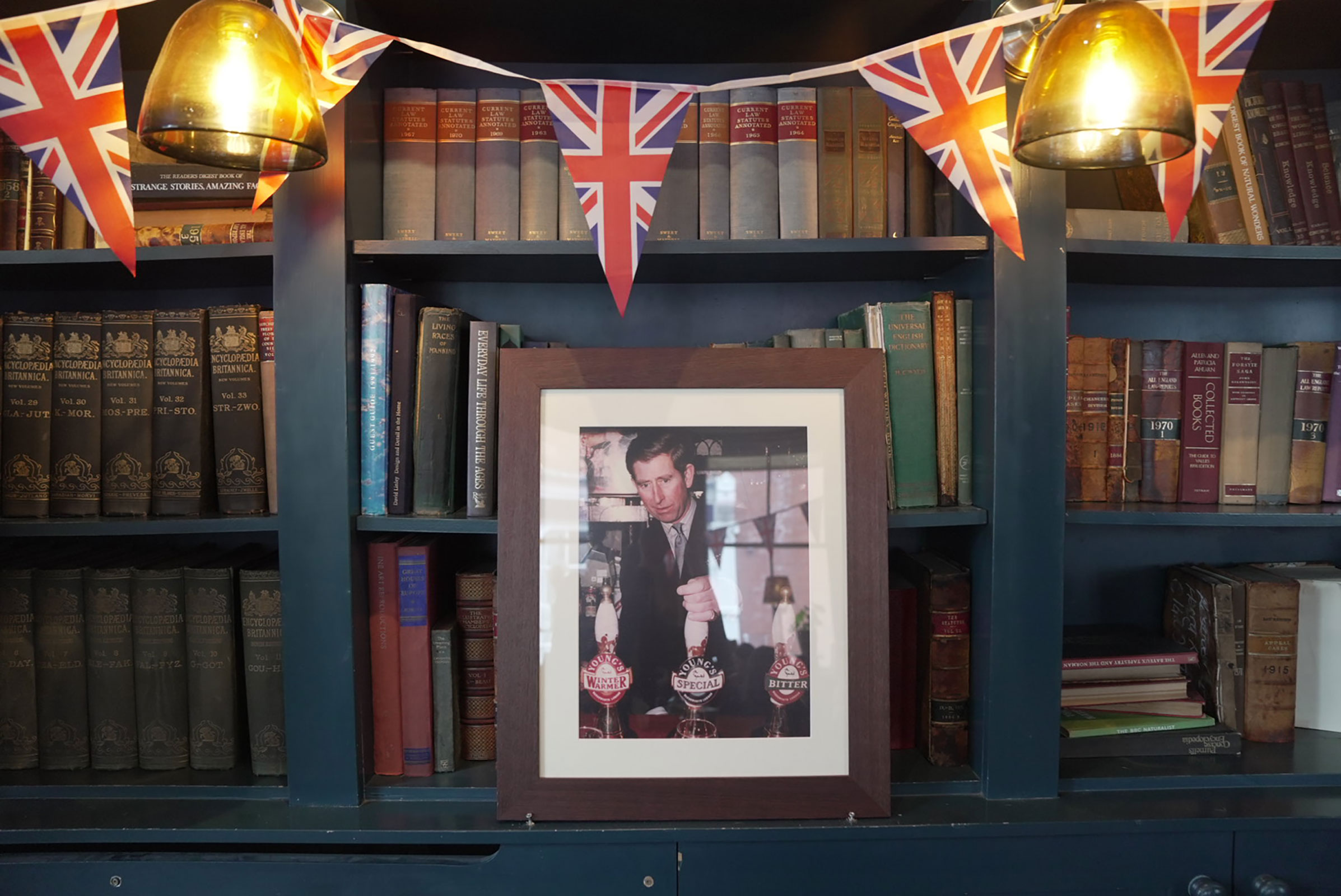A framed photo of King Charles III sits on a bookshelf at The Phoenix in Chelsea.