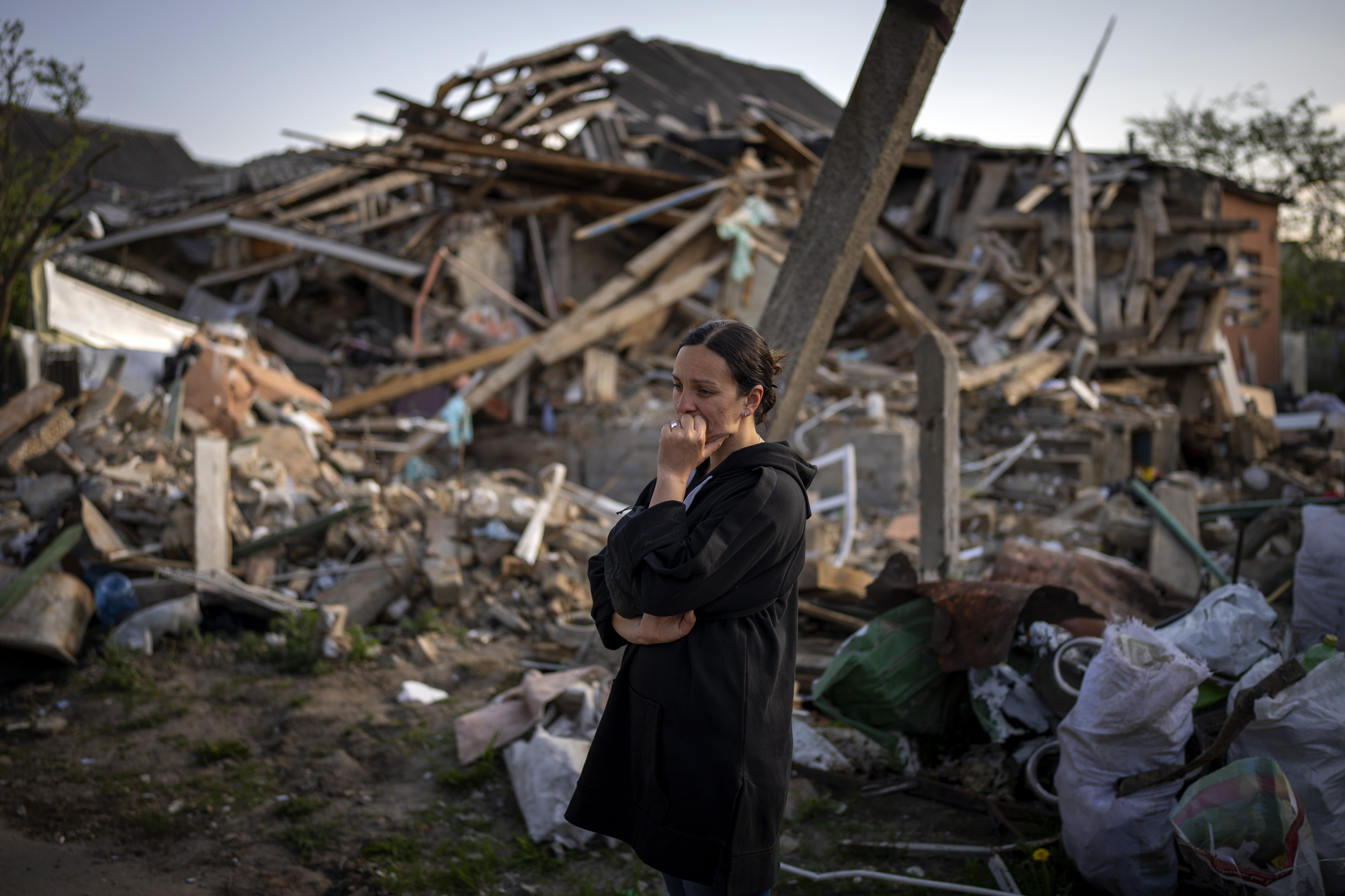 Anna Shevchenko, 35, reacts next to her home in Irpin, near Kyiv, Tuesday, May 3, 2022. The house, built by Shevchenko's grandparents, was nearly completely destroyed by bombing in late March during the Russian invasion of Ukraine. 
