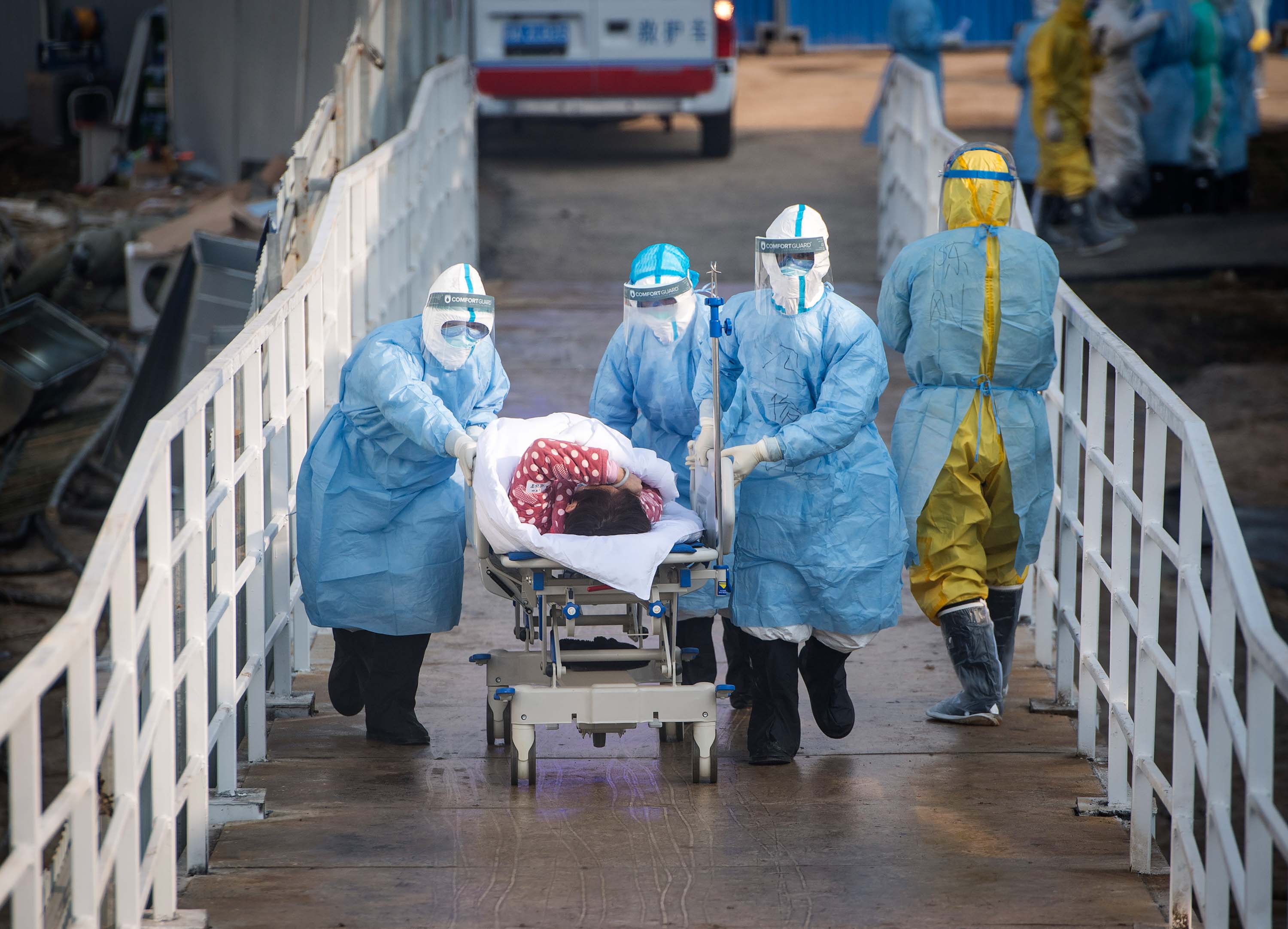 In this photo released by China's Xinhua News Agency on Tuesday, medical workers in protective suits help transfer the first group of patients into the newly-completed Huoshenshan temporary field hospital in Wuhan.