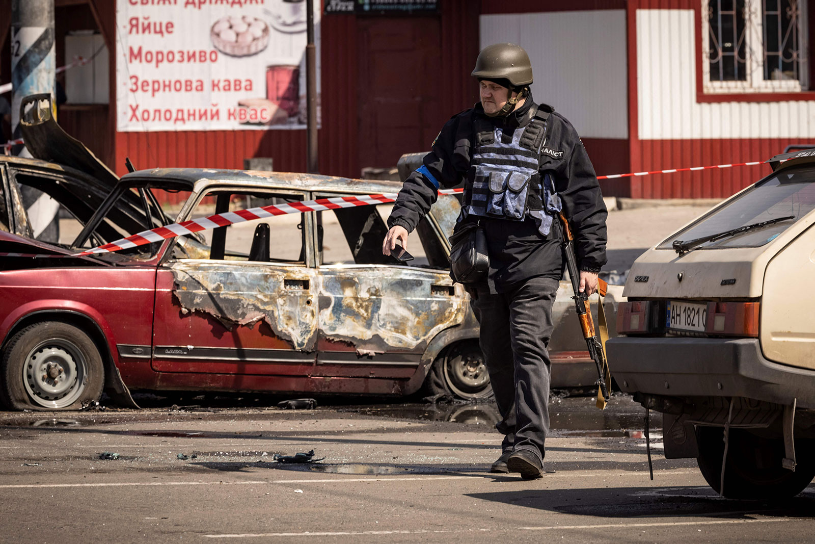 A Ukrainian policeman walks past damaged vehicles outside a train station in Kramatorsk, Ukraine, on April 8. 