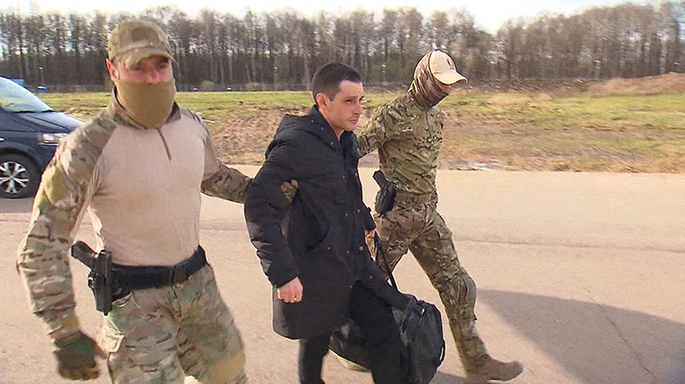 In an image taken from video released on April 27, former U.S. Marine Trevor Reed is escorted to a plane by Russian service members as part of a prisoner swap between the US and Russia, in Moscow, Russia.