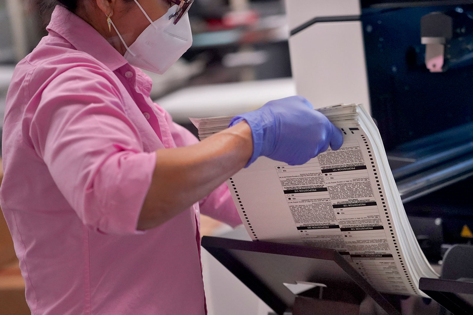 An election worker removes tabulated ballots from the machine inside the Maricopa County Recorders Office on Thursday, November 10, in Phoenix. 