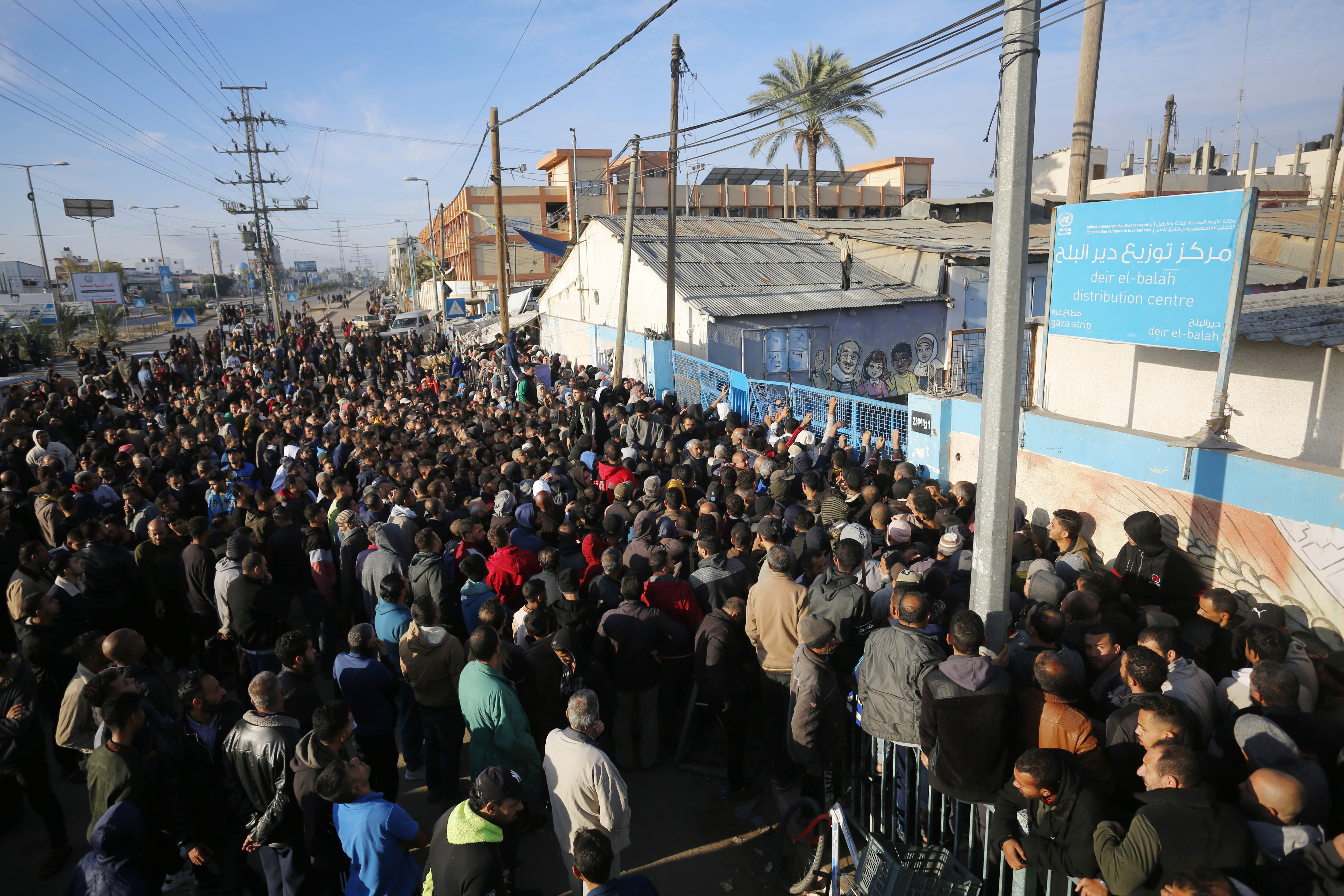 People line up for flour being distributed by the United Nations Relief and Works Agency for Palestine Refugees in the Near East (UNRWA), in Deir al-Balah, Gaza, on December 7.
