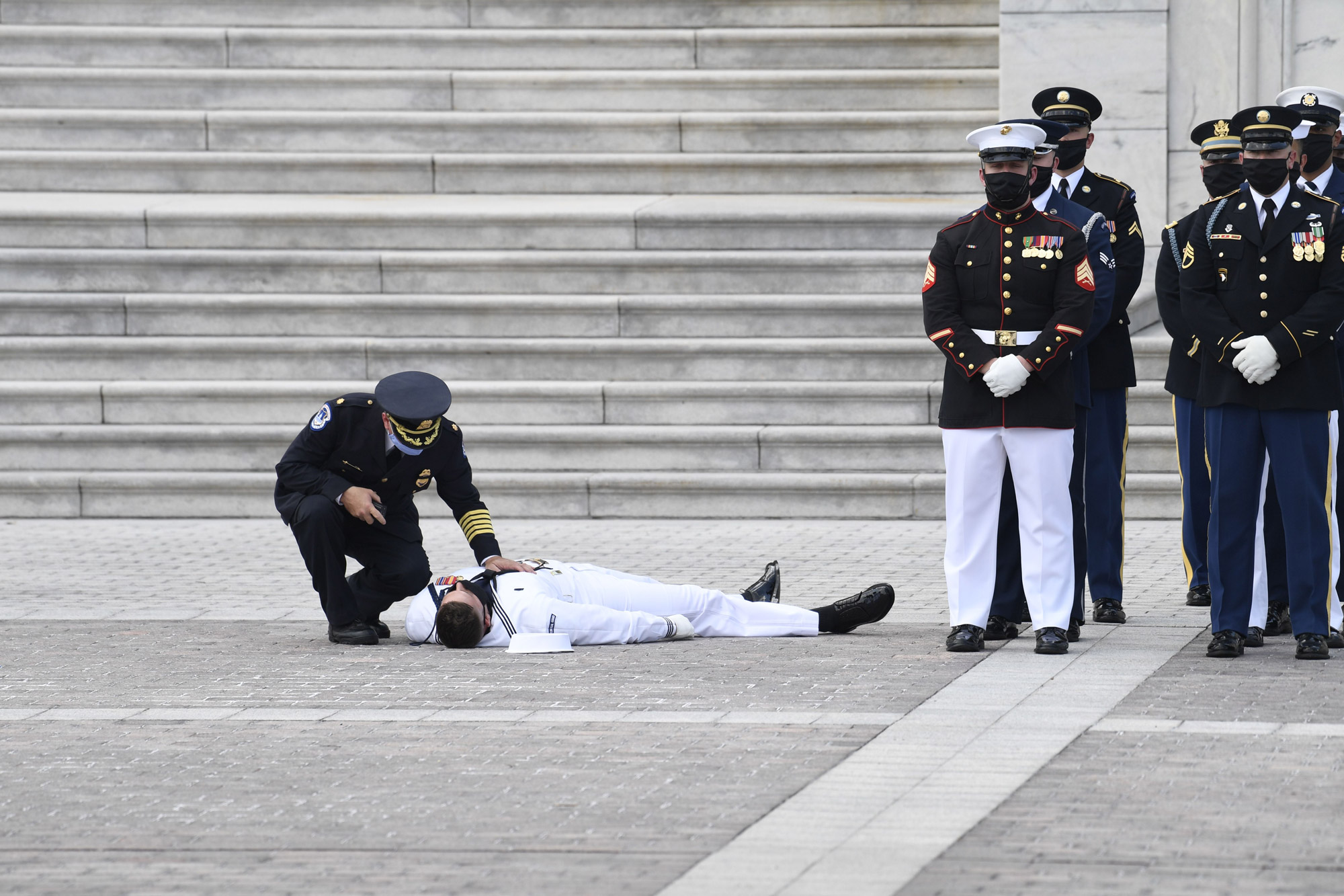 A member of a US military honor guard is checked on after collapsing in the heat of the day as a hearse carrying the casket of civil rights pioneer and longtime US Representative John Lewis arrives outside the US Capitol prior to the start of the ceremony preceding the lying in state of John Lewis in the Rotunda of the US Capitol in Washington, DC, on July 27. 