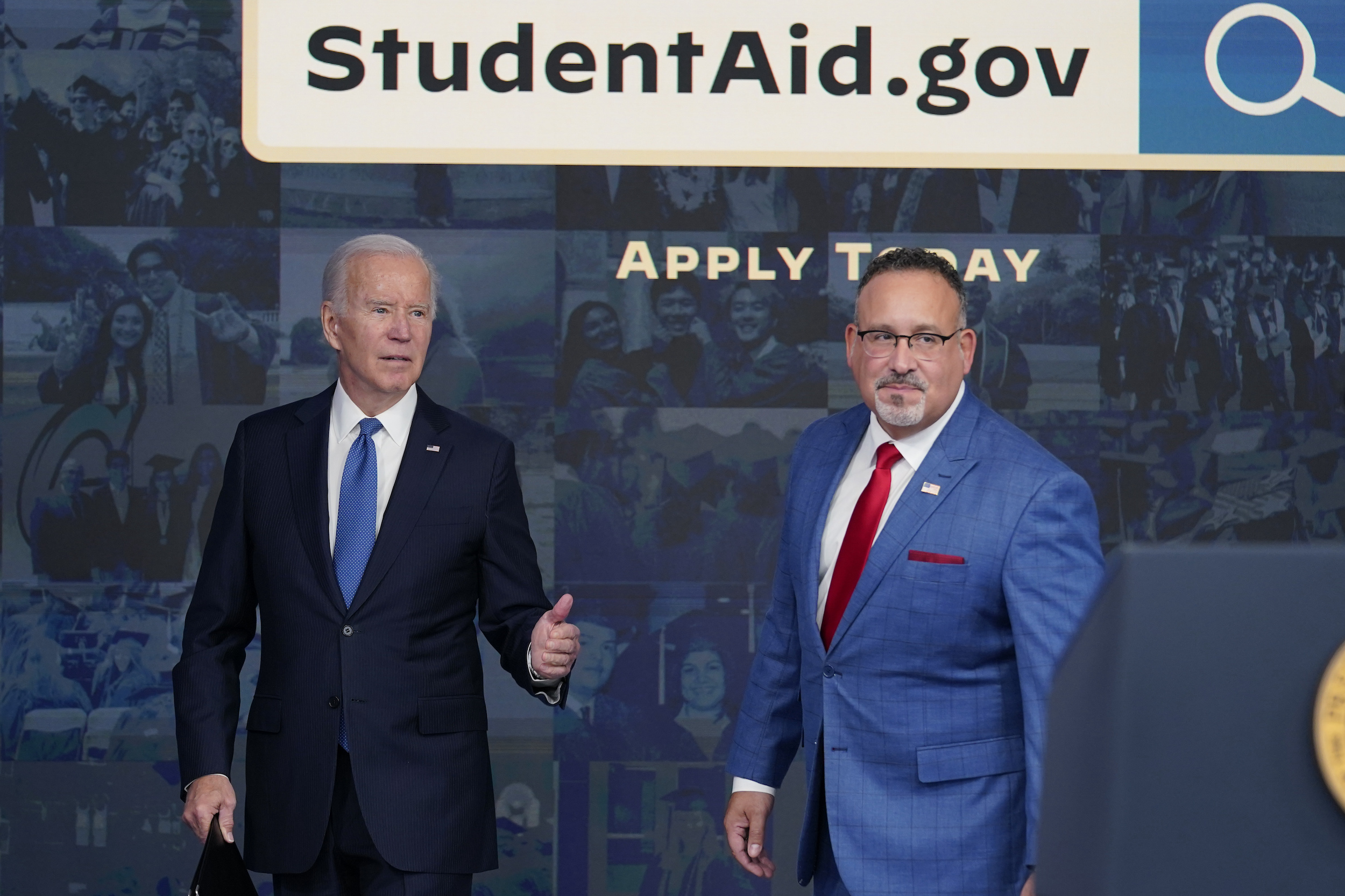 President Joe Biden answers questions with Education Secretary Miguel Cardona as they leave an event about the student debt relief portal beta test at the White House complex on October 17.