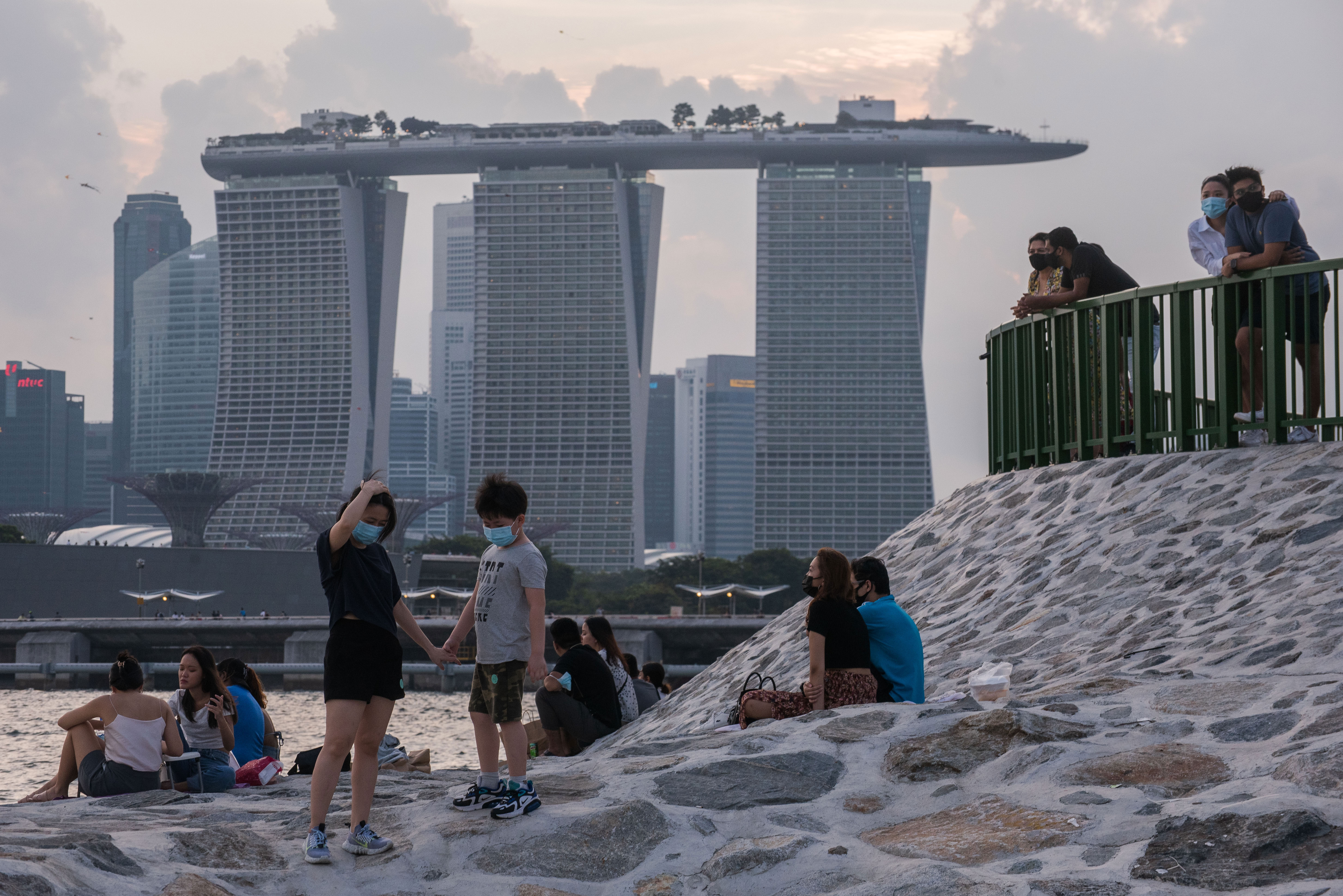People in Singapore relax on a breakwater with the Marina Bay Sands in the background on June 6.