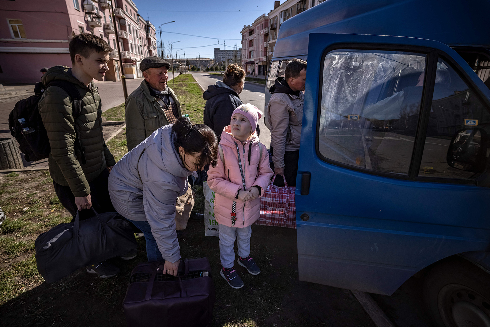 People wait for a bus as a children looks at the sky, a day after a rocket attack at a train station, in Kramatorsk, Ukraine on April 9.