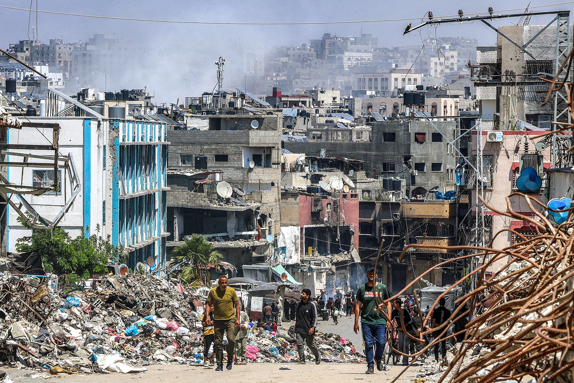 People walk past a mound of trash and destroyed buildings in Jabalya, Gaza, on May 14.