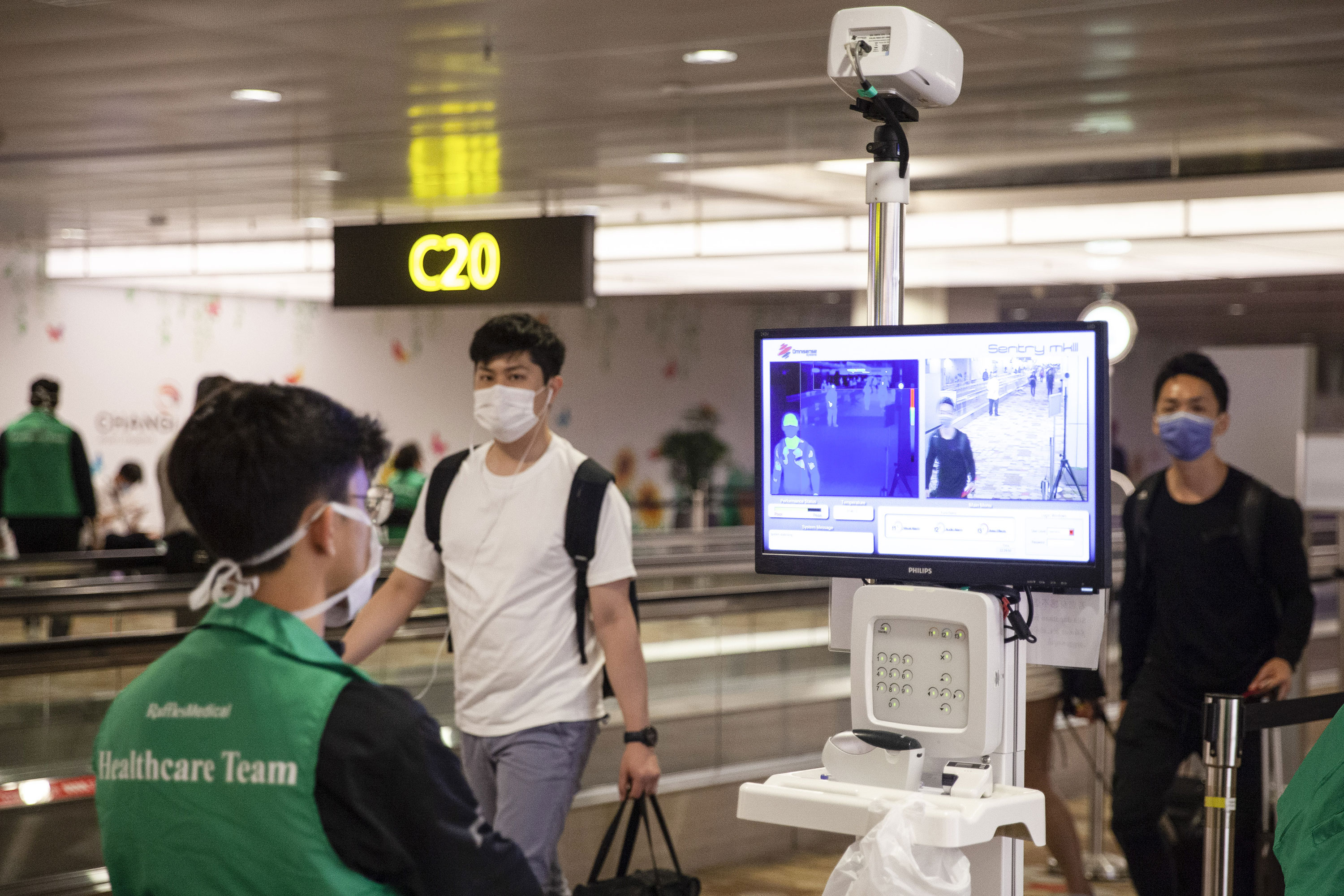 Passengers' temperatures are checked as travelers pass through Changi Airport in Singapore on March 11.