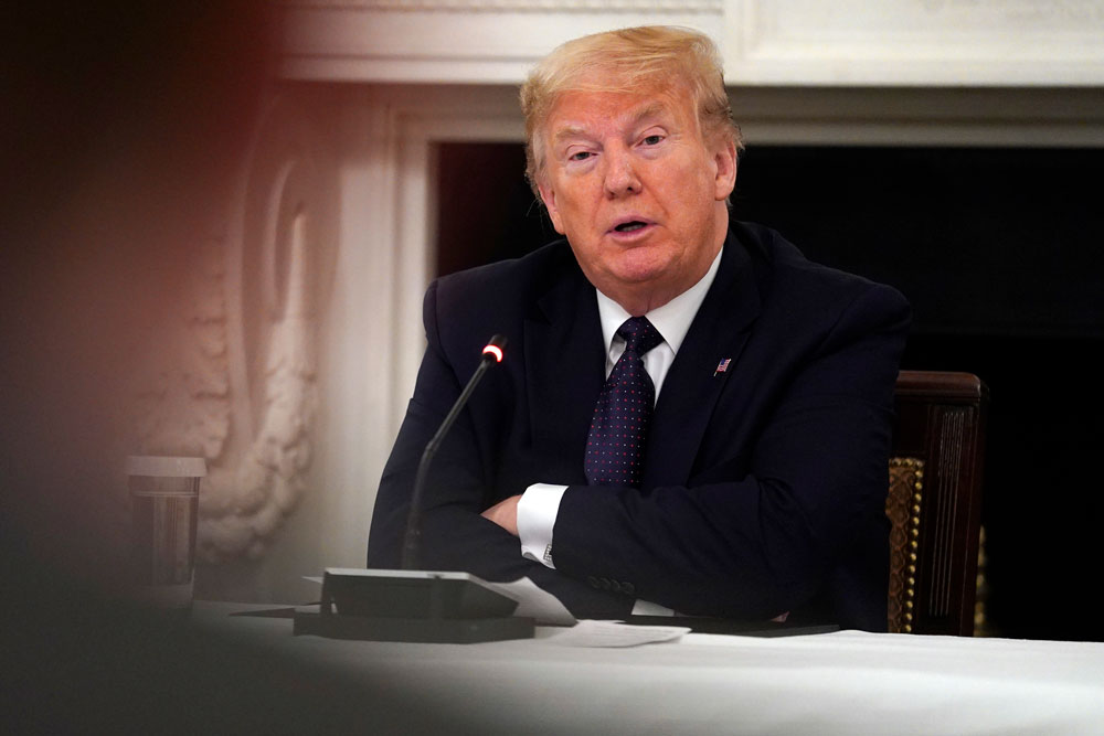 President Donald Trump listens during a meeting with restaurant industry executives about the coronavirus response, in the State Dining Room of the White House, on Monday, May 18, in Washington.