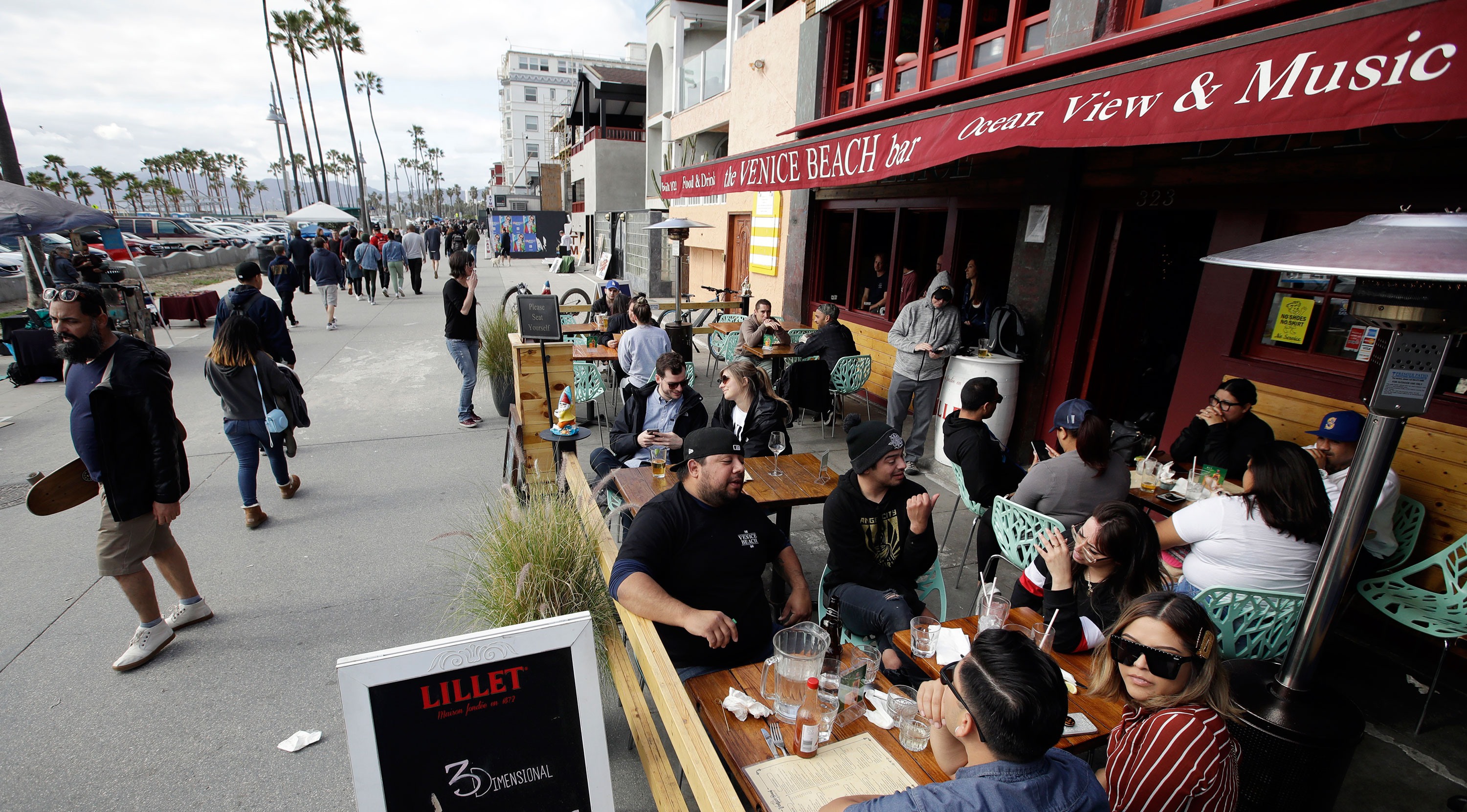 Patrons sit outside a bar along the Venice Beach Boardwalk on Sunday in Los Angeles.