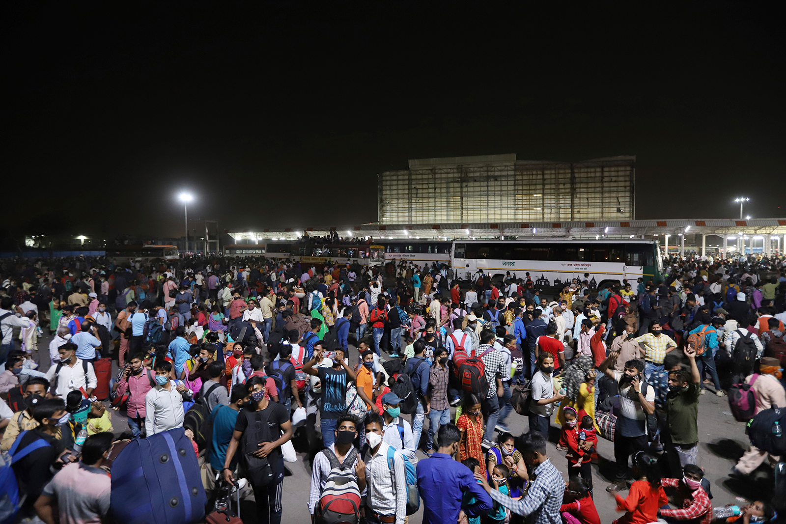 Hundreds of migrant workers in New Delhi wait at a bus station to leave for their villages on Monday.