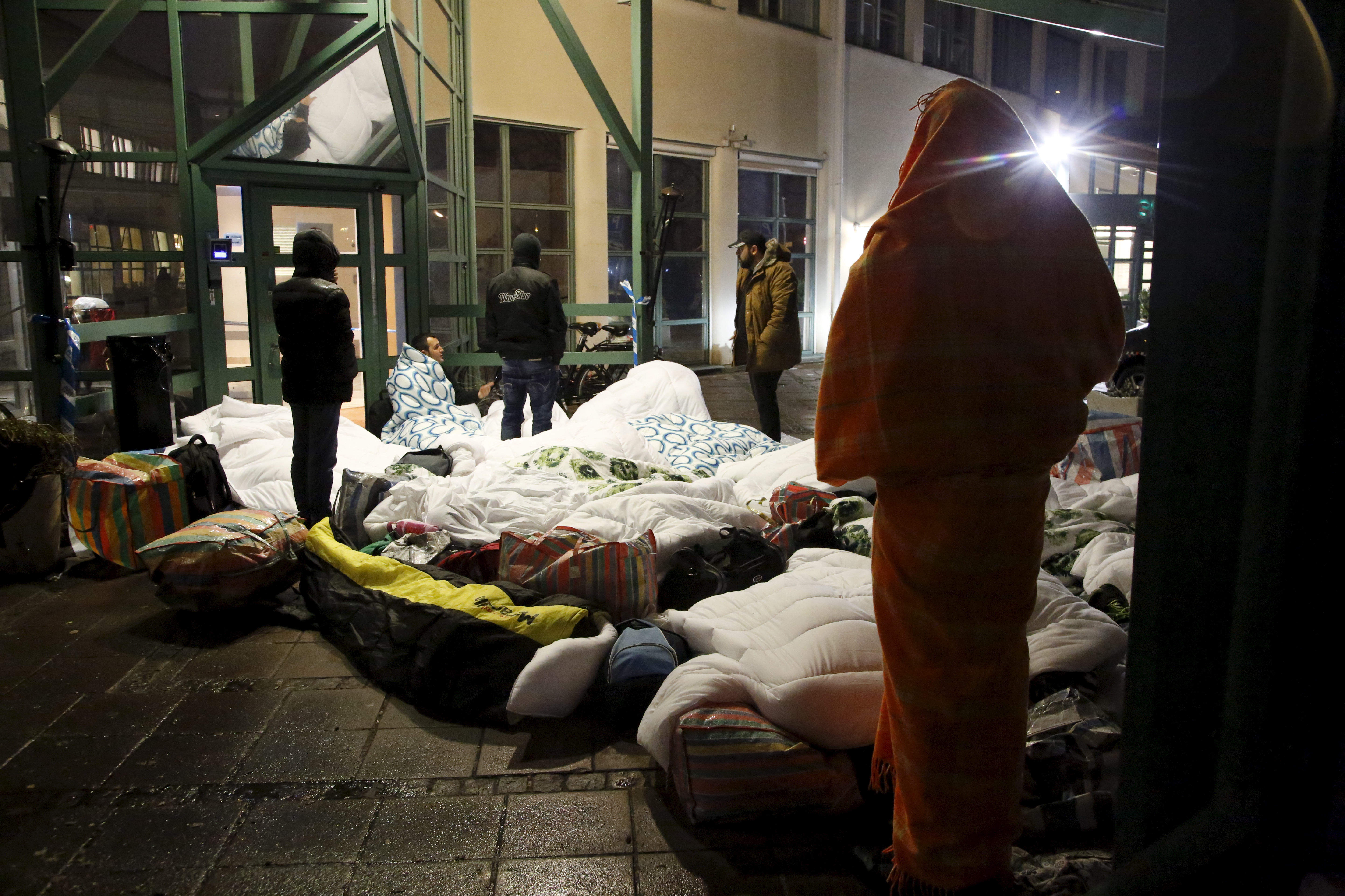 People sleep outside the entrance of the Swedish Migration Agency's arrival center for asylum seekers, in Malmo, Sweden in 2015.  