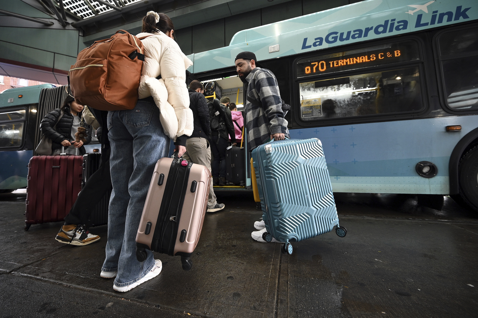 Travelers board a bus to LaGuardia Airport in New York City on Wednedsay.