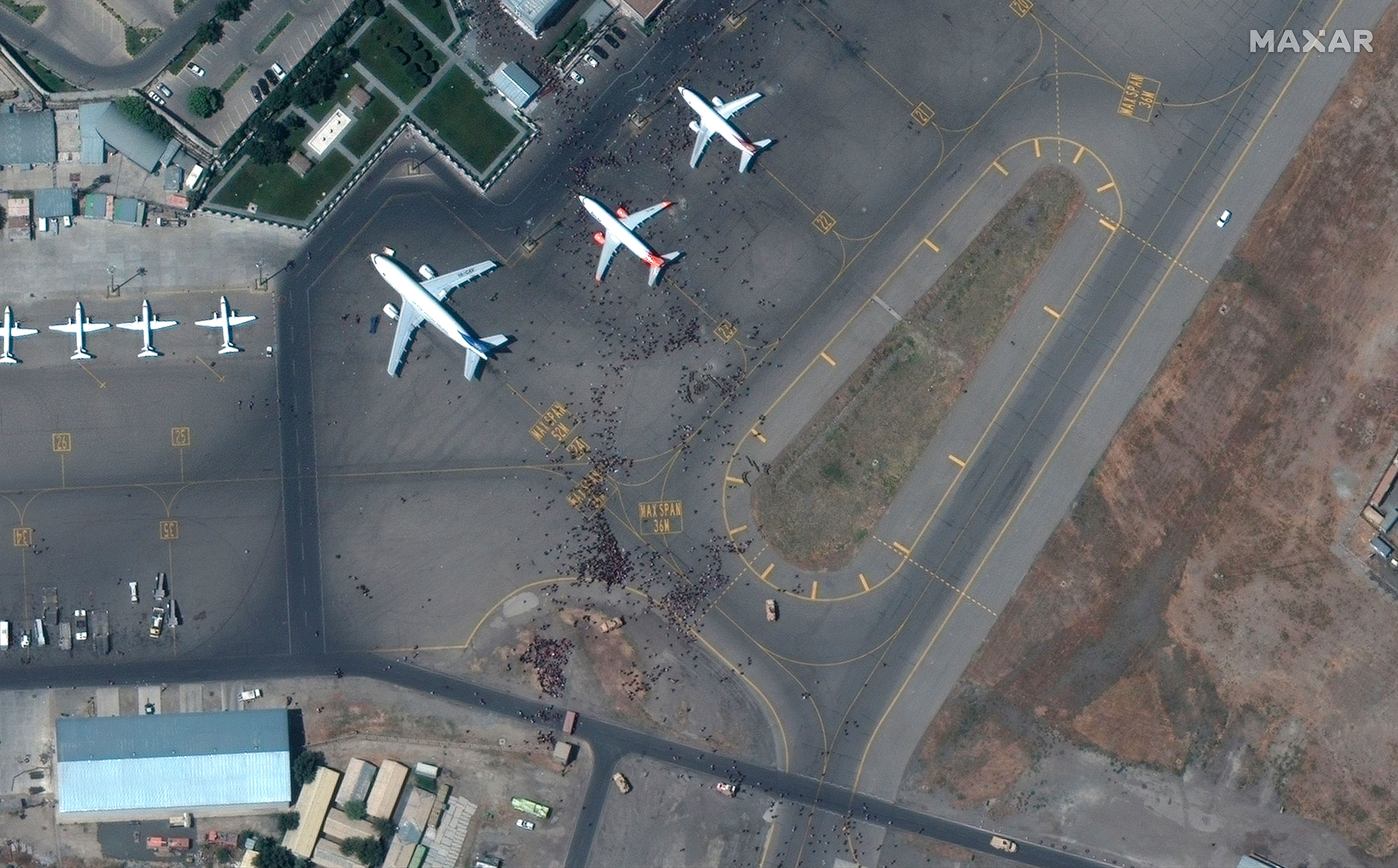 This satellite photo from Maxar Technologies shows swarms of people on the tarmac at Kabul International Airport, Monday August 16.