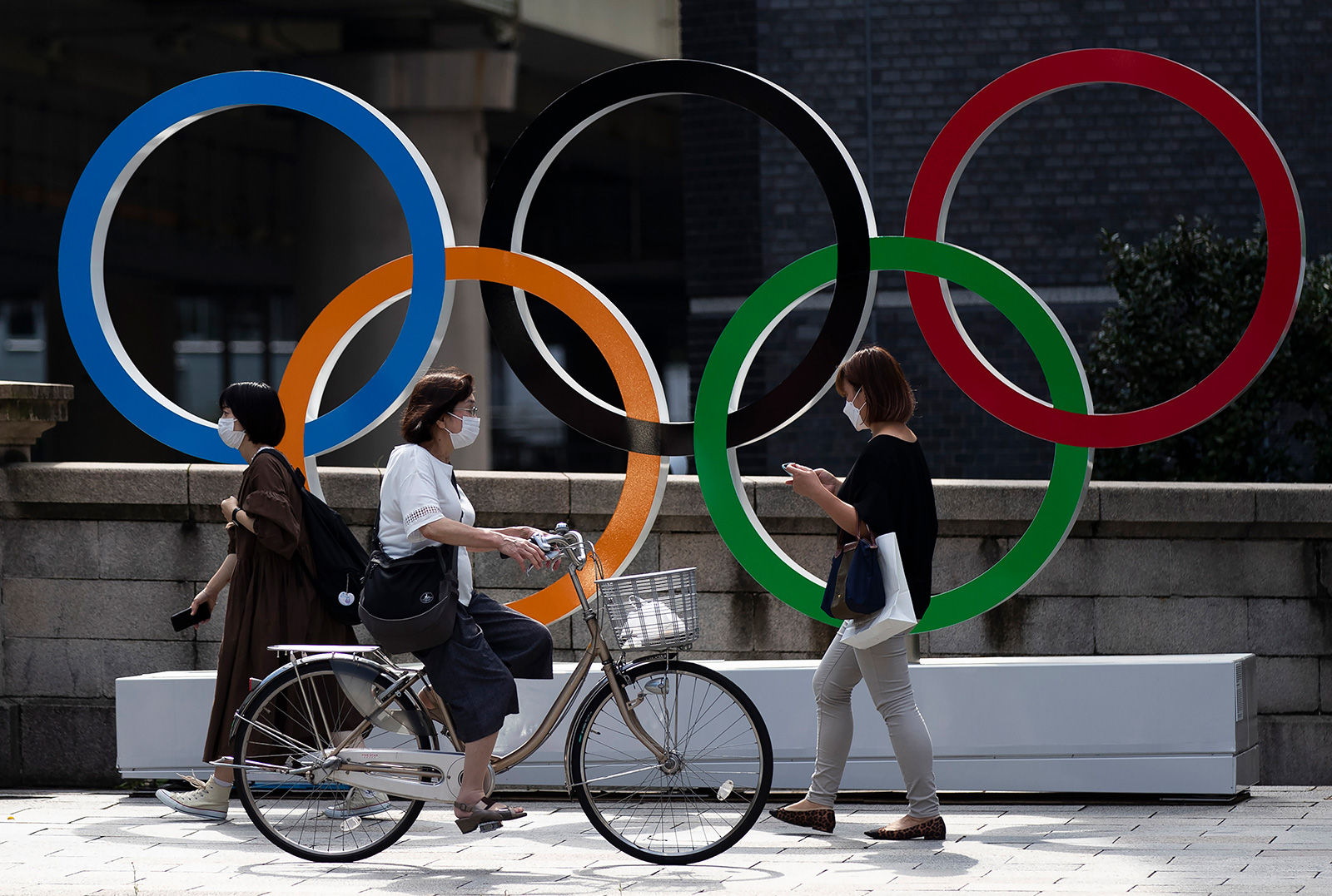 People walk by the Olympic rings installed by the Nippon Bashi bridge in Tokyo on Thursday, July 15.