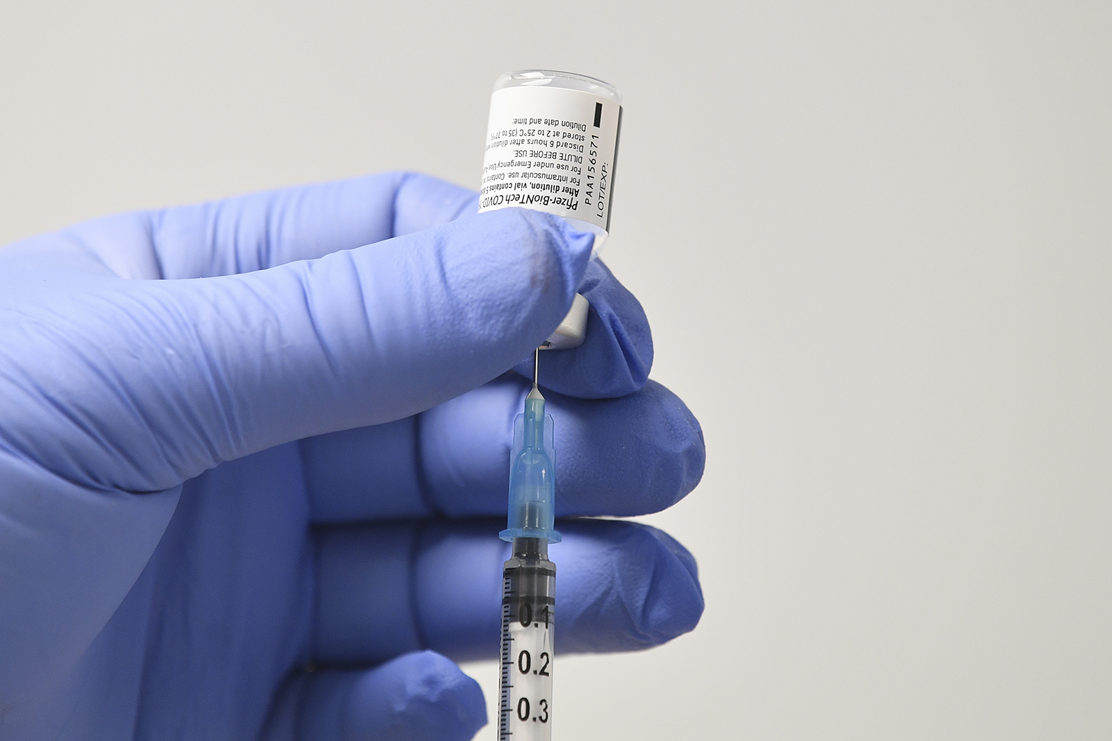 A member of staff uses a needle and a vial of Pfizer-BioNTech Covid-19 vaccine to prepare a dose at a vaccination health center on December 8, in Cardiff, UK.
