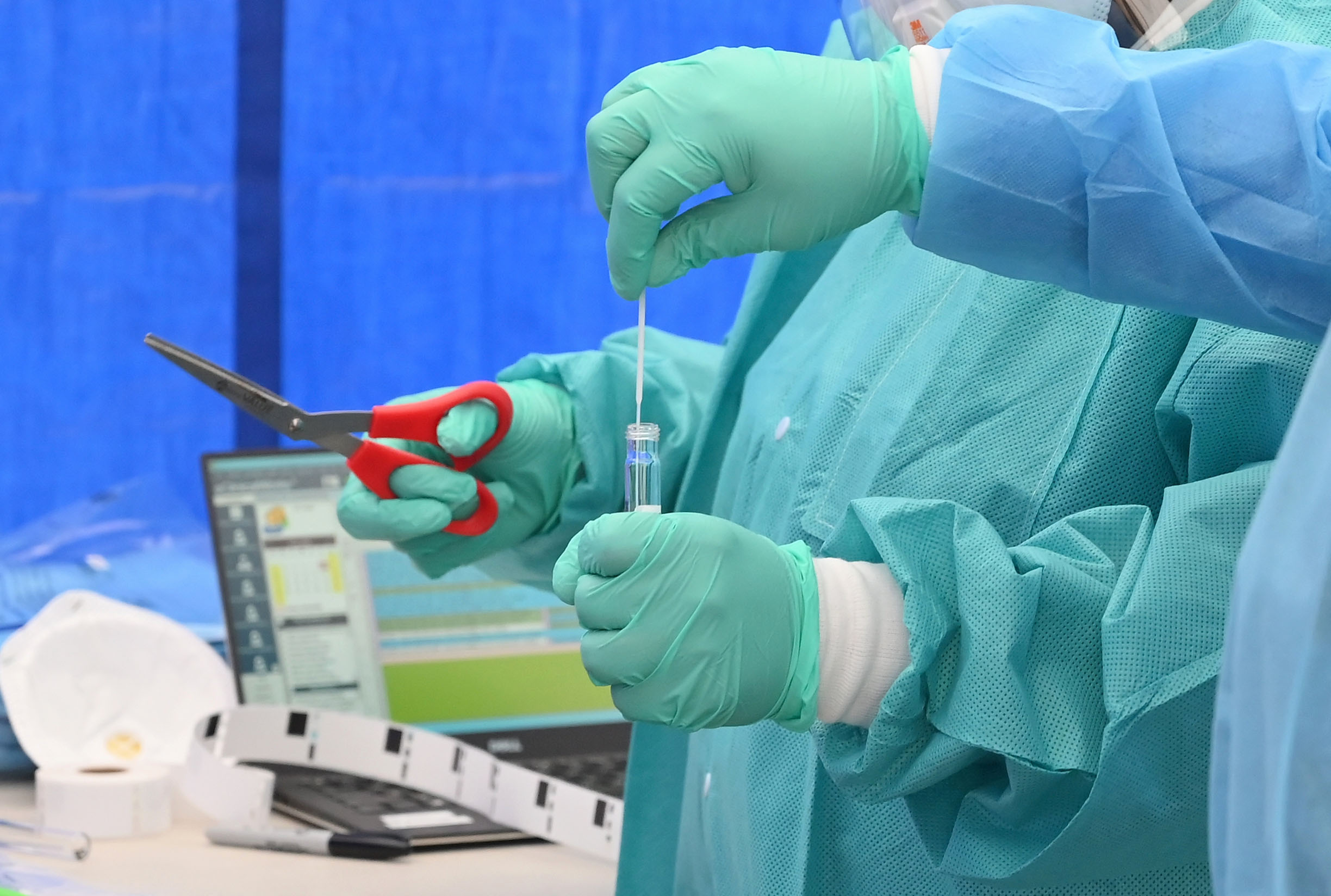 Health care workers at a Covid-19 testing site in Brooklyn, New York, place a patient's nasal swab into a tube on May 8.