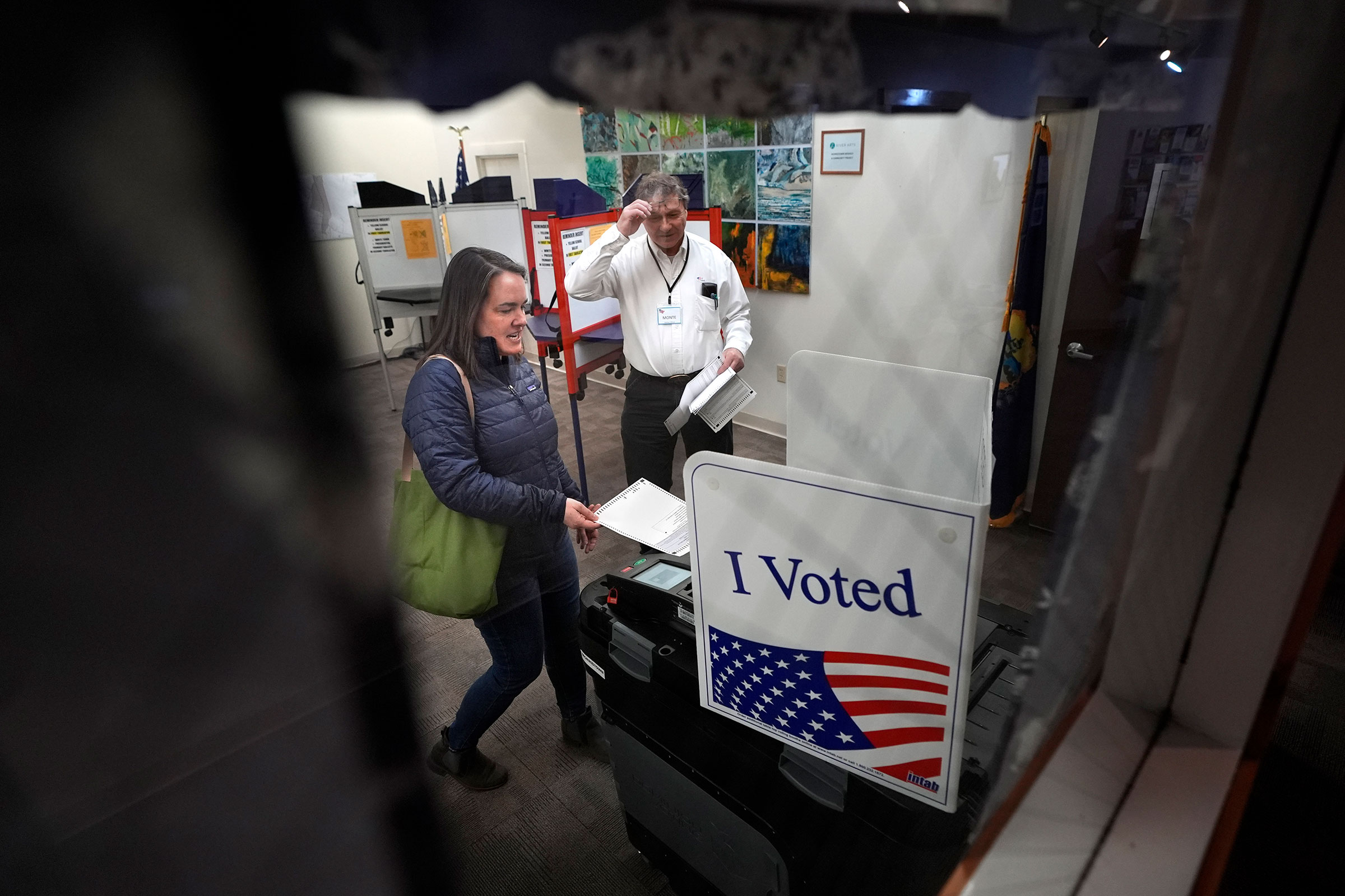 Amber Cutler casts her ballot as election official Monte Mason looks on during primary election voting on Tuesday at Morrisville town hall in Vermont.
