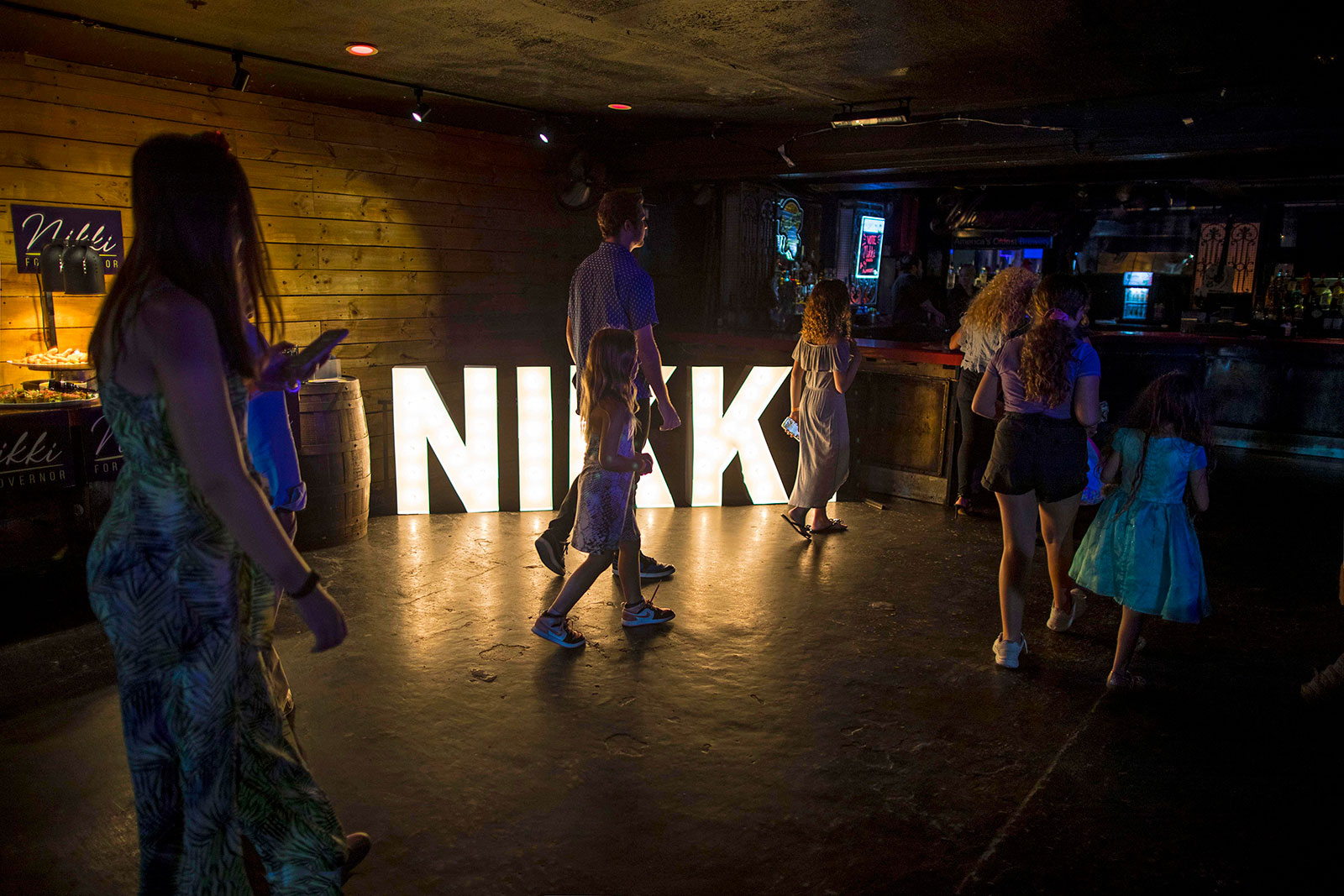 People walk past a sign spelling ‘Nikki’ at an election night event for Agriculture Commissioner Nikki Fried on Tuesday.
