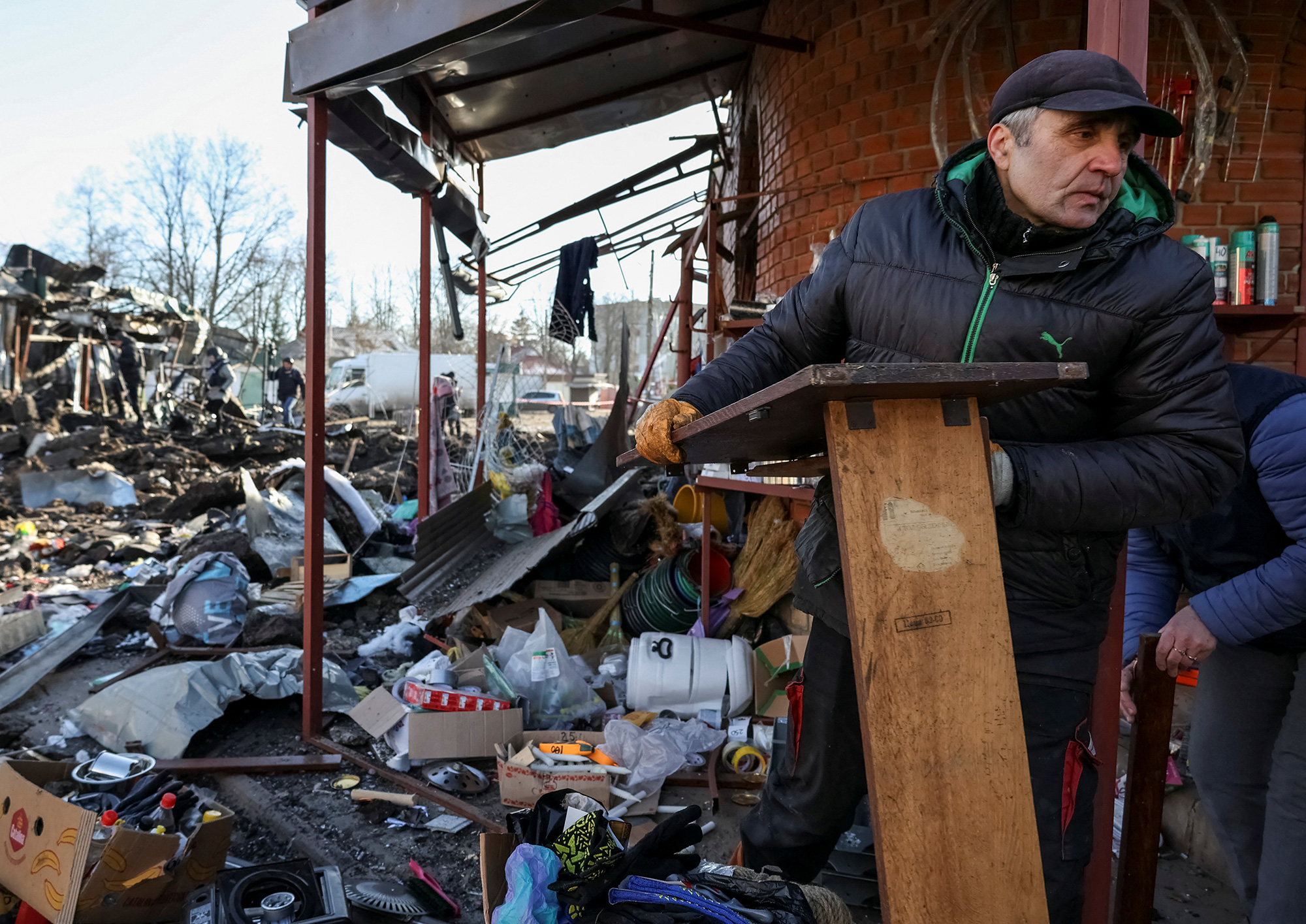 Local residents look through items at a site of the local market heavily damaged by a Russian missile strike in Shevchenkove, Kharkiv region, Ukraine, on Monday, January 9. 