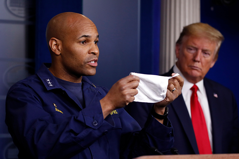 President Donald Trump watches as US Surgeon General Jerome Adams holds up his face mask as he speaks about the coronavirus in the James Brady Press Briefing Room of the White House, Wednesday, April 22.