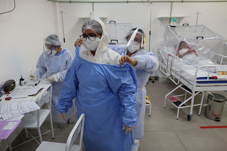 A health worker helps a woman put on protective gear at the Intensive Care Unit for COVID-19 of the Gilberto Novaes Hospital in Manaus, Brazil, on May 20.