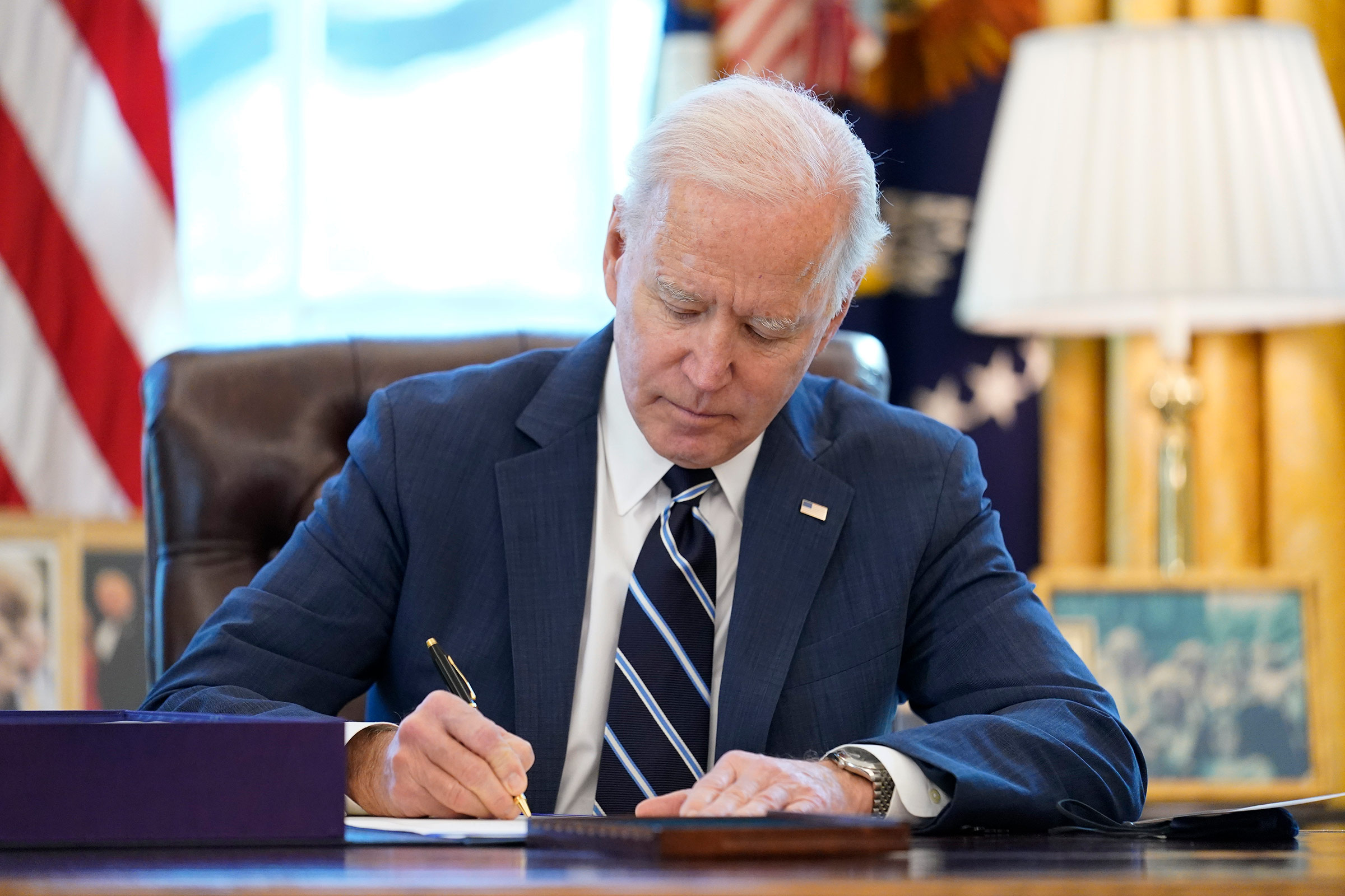 President Joe Biden signs the American Rescue Plan in the Oval Office of the White House on March 11, in Washington, DC. 