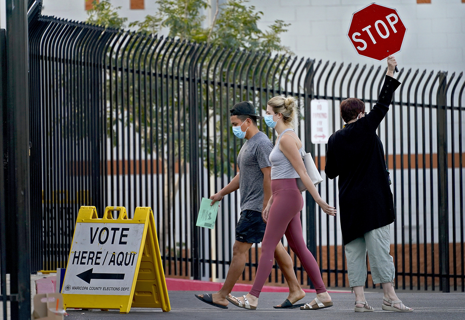 A school crossing guard stops cars for voters entering a polling station, on Tuesday in Phoenix. 