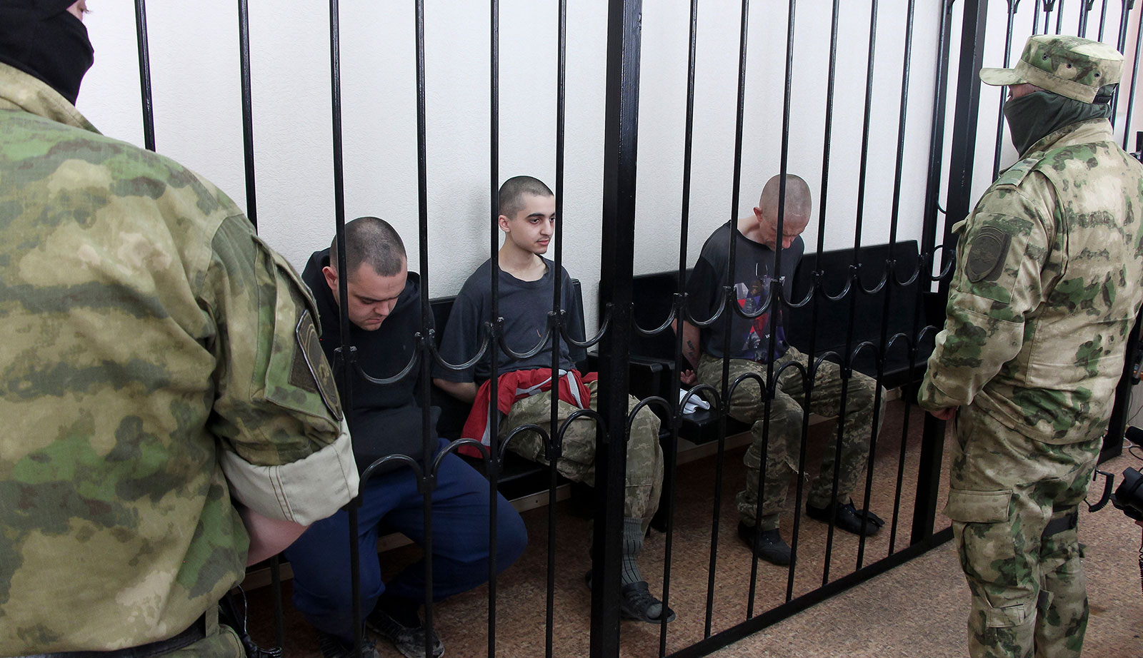 Two British citizens Aiden Aslin, left, and Shaun Pinner, right, and Moroccan Brahim Saadoune, center, sit behind bars in a courtroom in Donetsk, in the territory which is under the Government of the Donetsk People's Republic control, eastern Ukraine, on June 9.