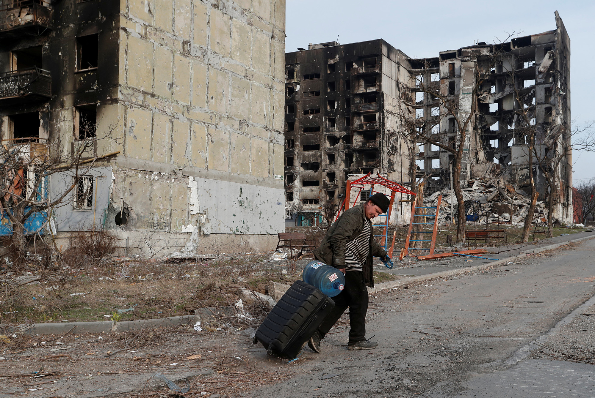 A local resident walks with a suitcase past destroyed apartment buildings in the besieged southern port city of Mariupol, Ukraine, on March 30.
