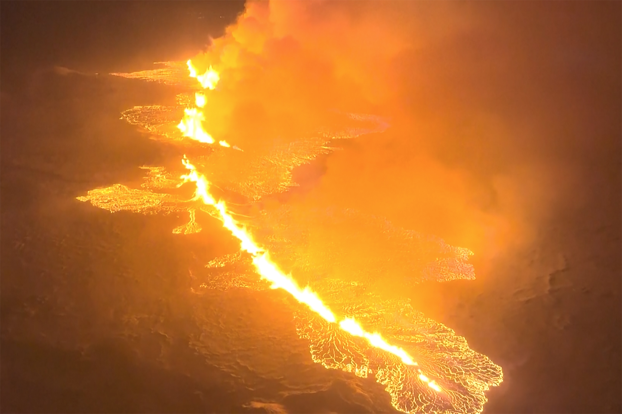 This image made from video and provided by the Icelandic Coast Guard shows magma flowing on a hill near Grindavik, Iceland, late Monday night.