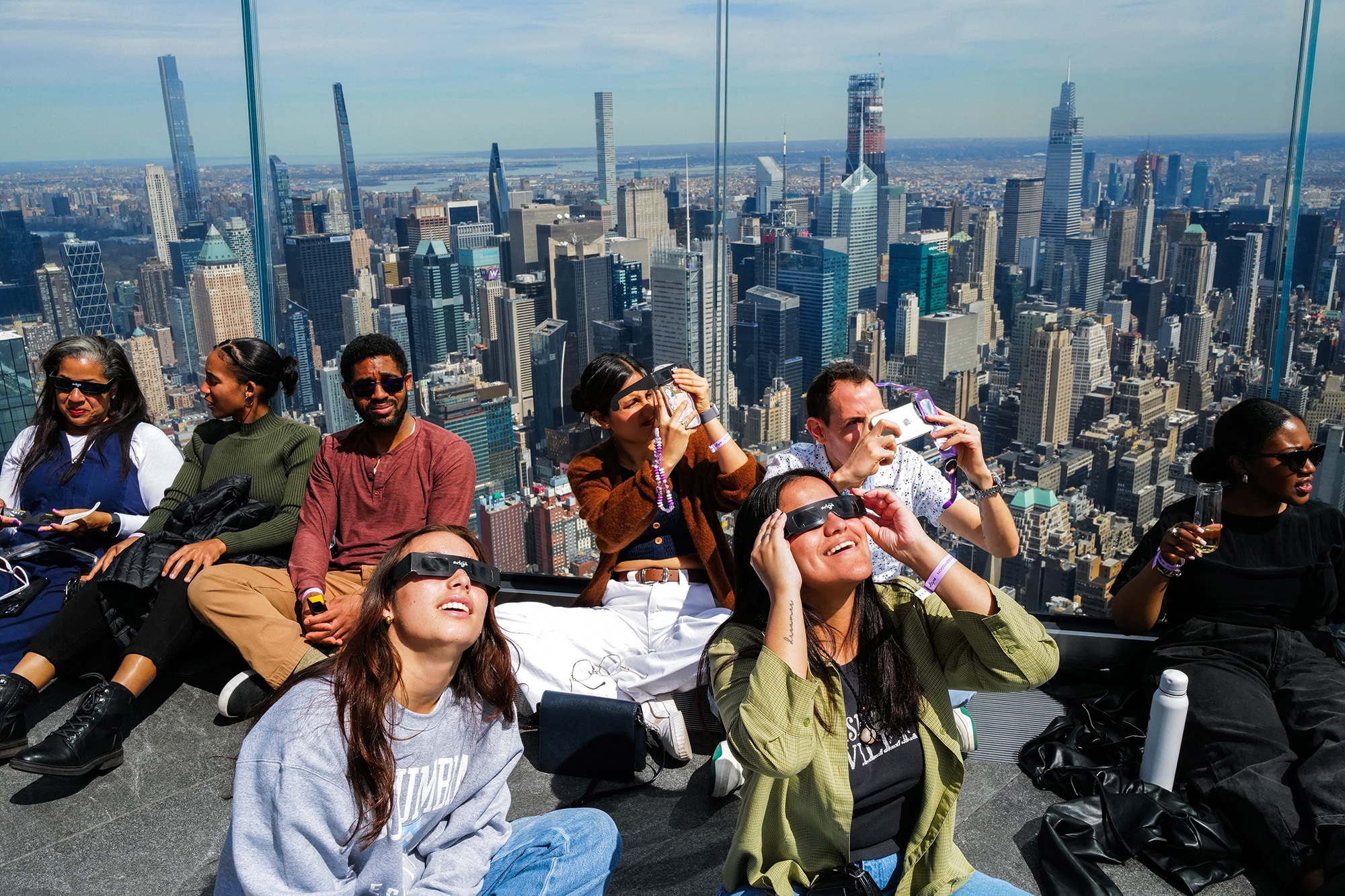 People look toward the sky at the 'Edge at Hudson Yards' observation deck in New York, on April 8, 2024. 