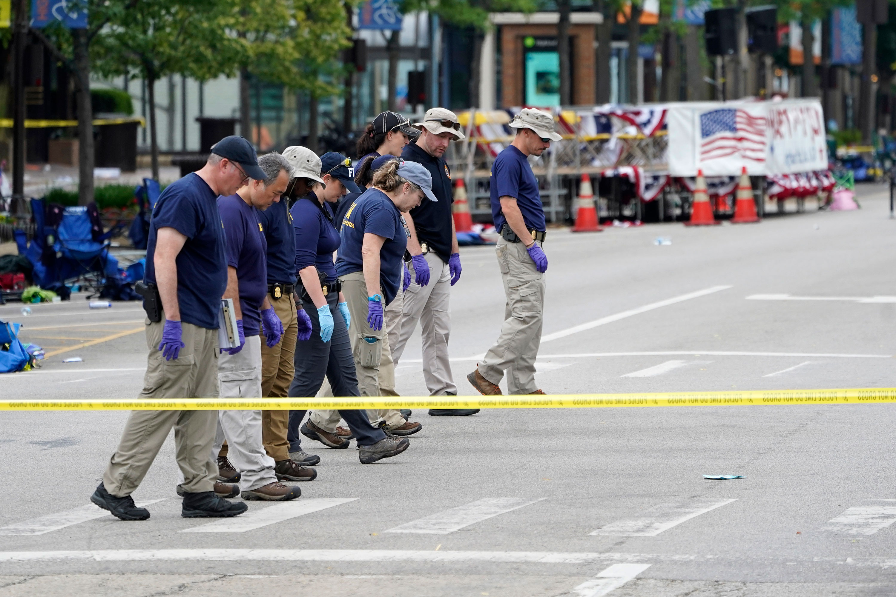 Members of the FBI walk the scene one day after the shooting in Highland Park, Illinois, on Tuesday.