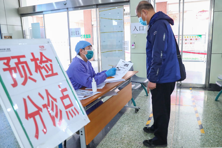 A staff member teaches a citizen how to register at Beijing Puren Hospital, which was used to be a designated hospital for treating coronavirus patients in Dongcheng District of Beijing, capital of China, March 23. 