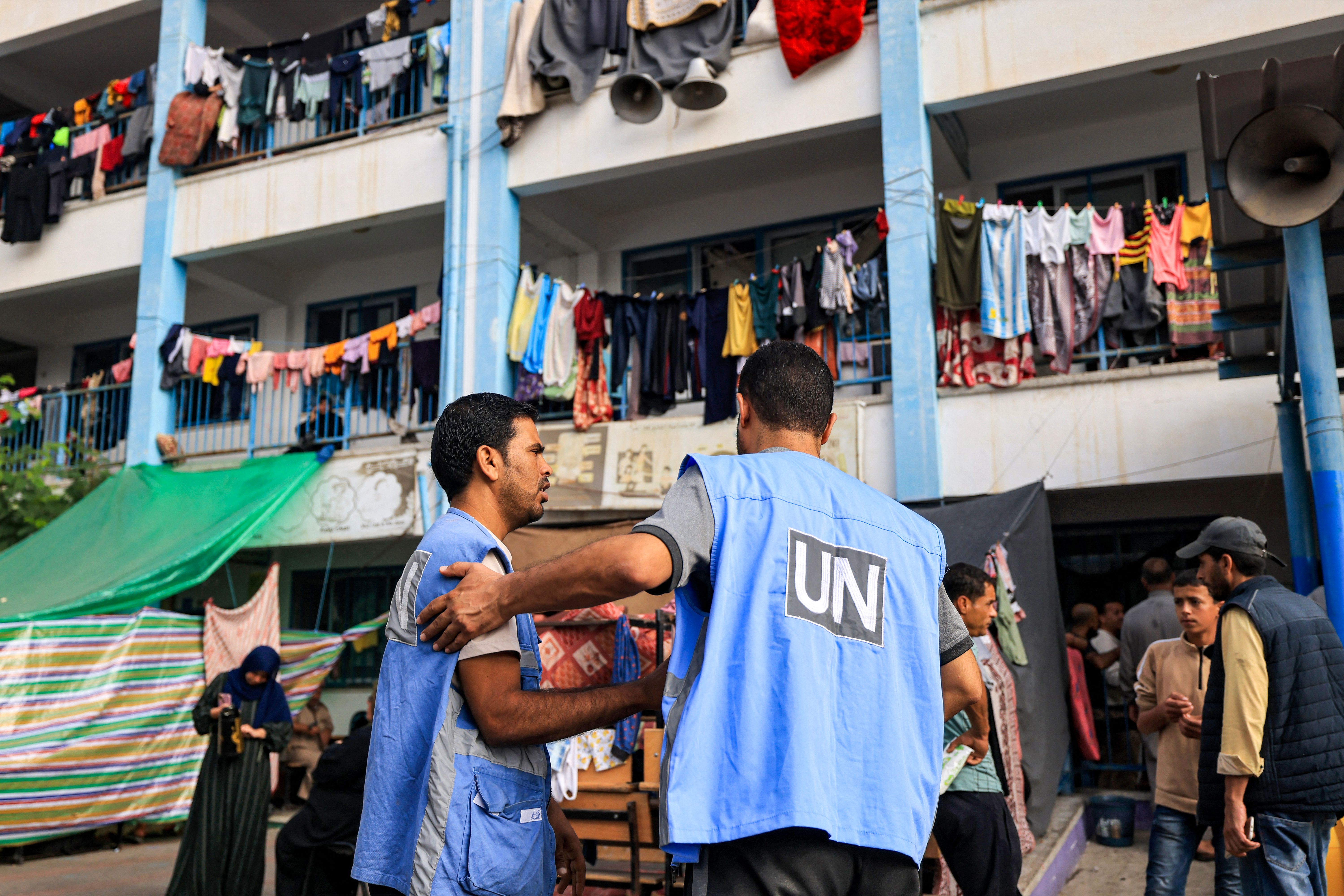 Workers of the United Nations Relief and Works Agency for Palestine Refugees (UNRWA) agency talk together in the playground of an UNRWA-run school that has been converted into a shelter for displaced Palestinians in Khan Younis, southern Gaza, on October 25.