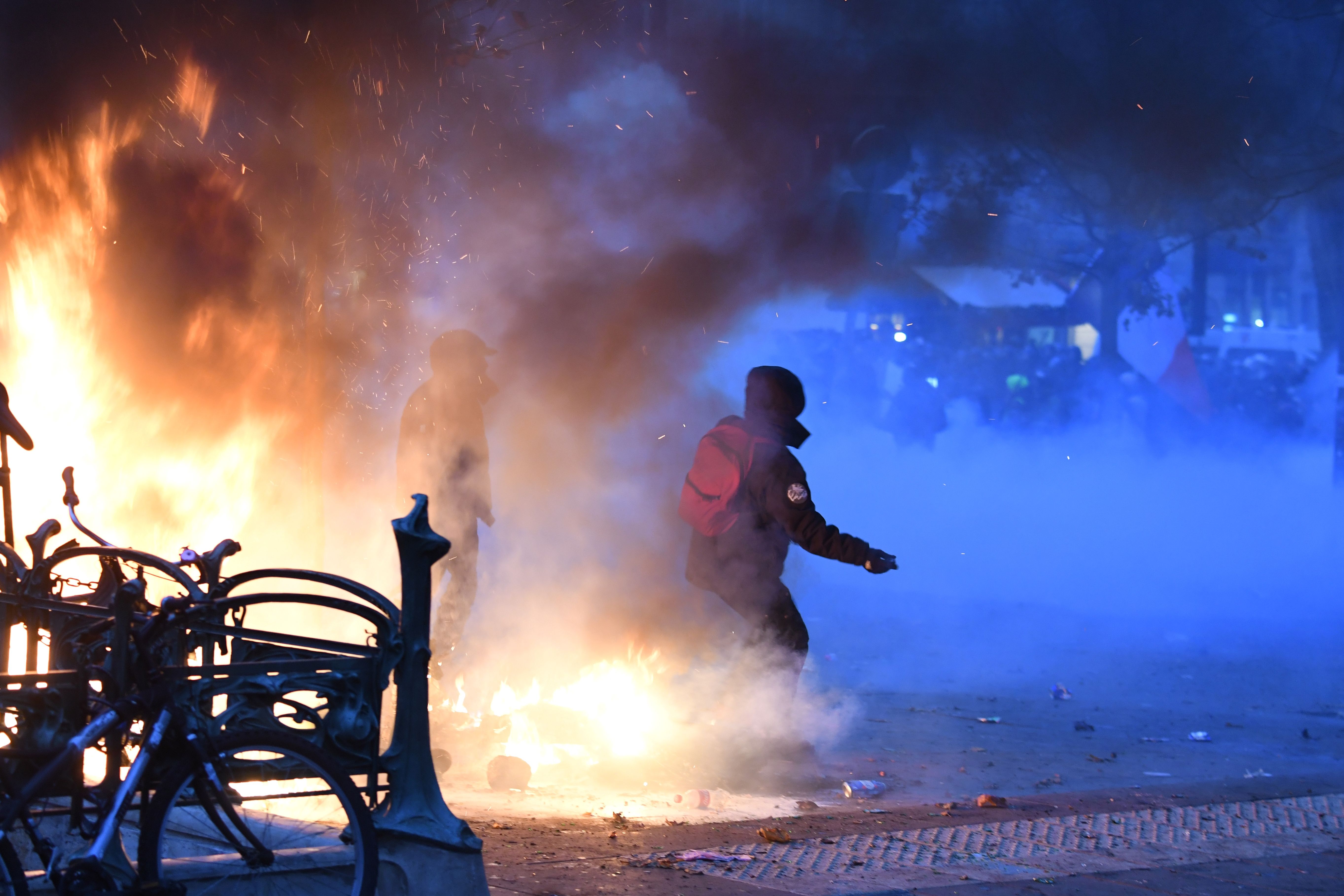Two protesters stand next to a fire in Paris.