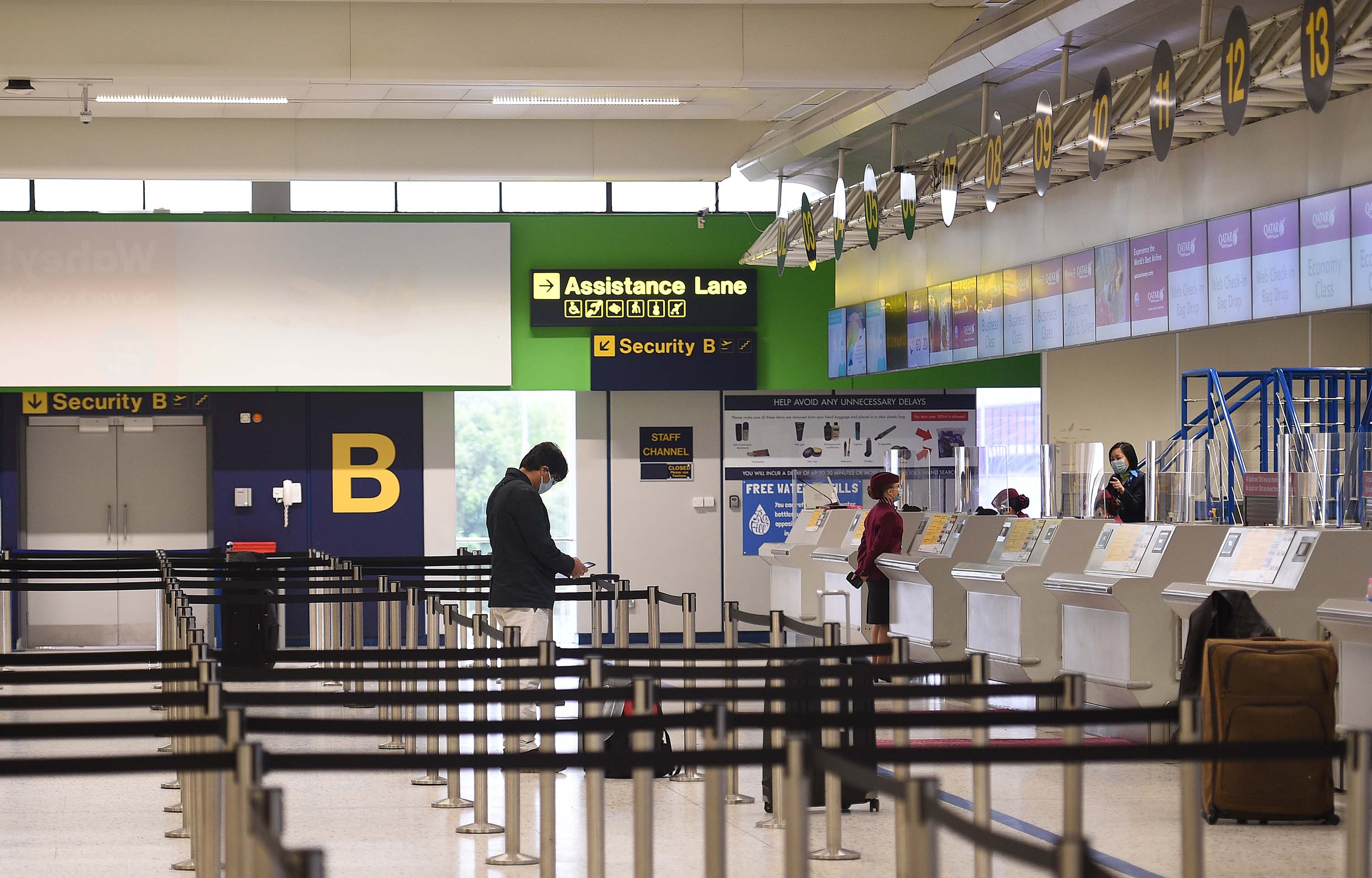 Passengers wearing PPE wait at a nearly deserted check-in desk in the Manchester Airport departure hall, in northern England, on May 11.