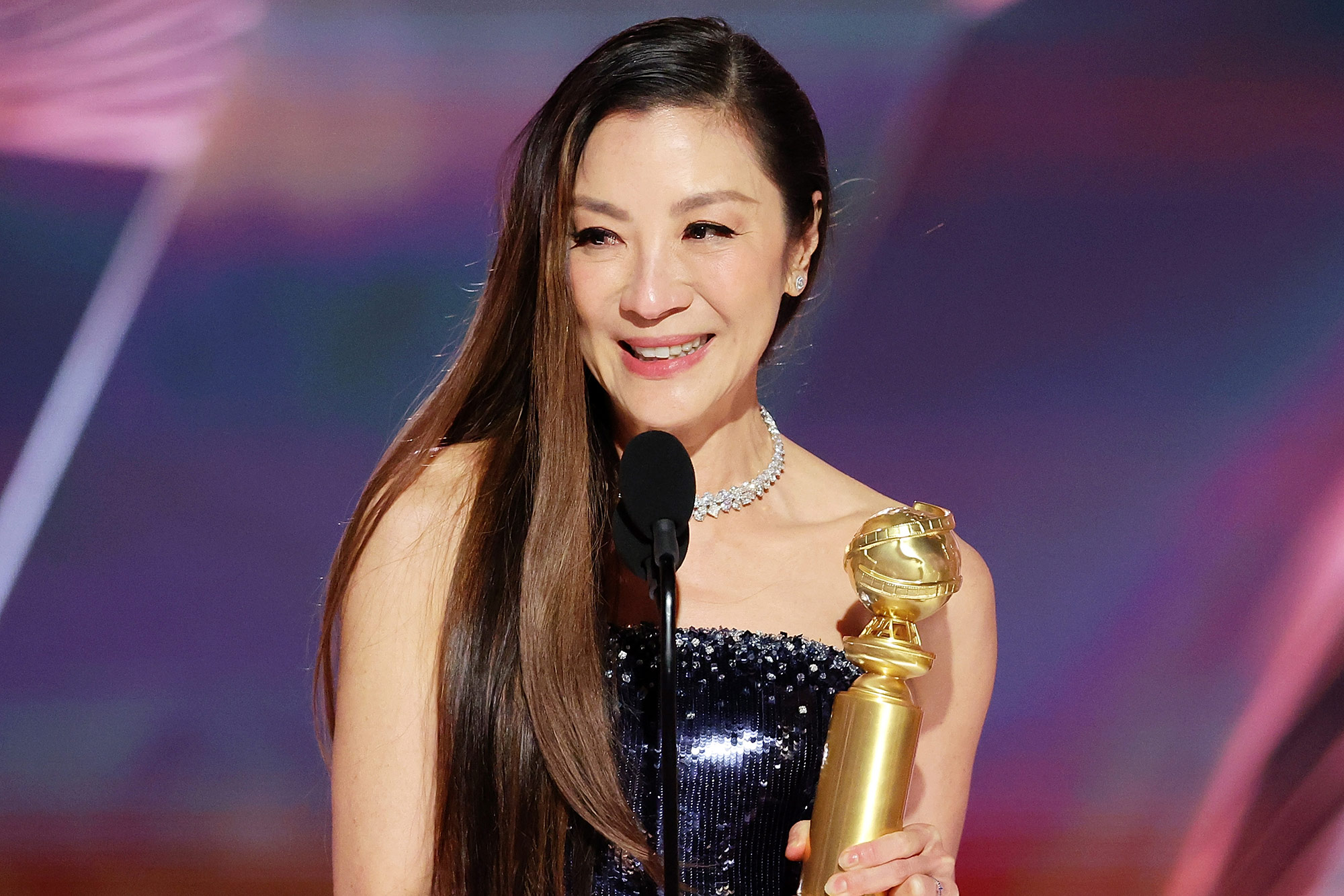 Michelle Yeoh accepts her award on stage. 