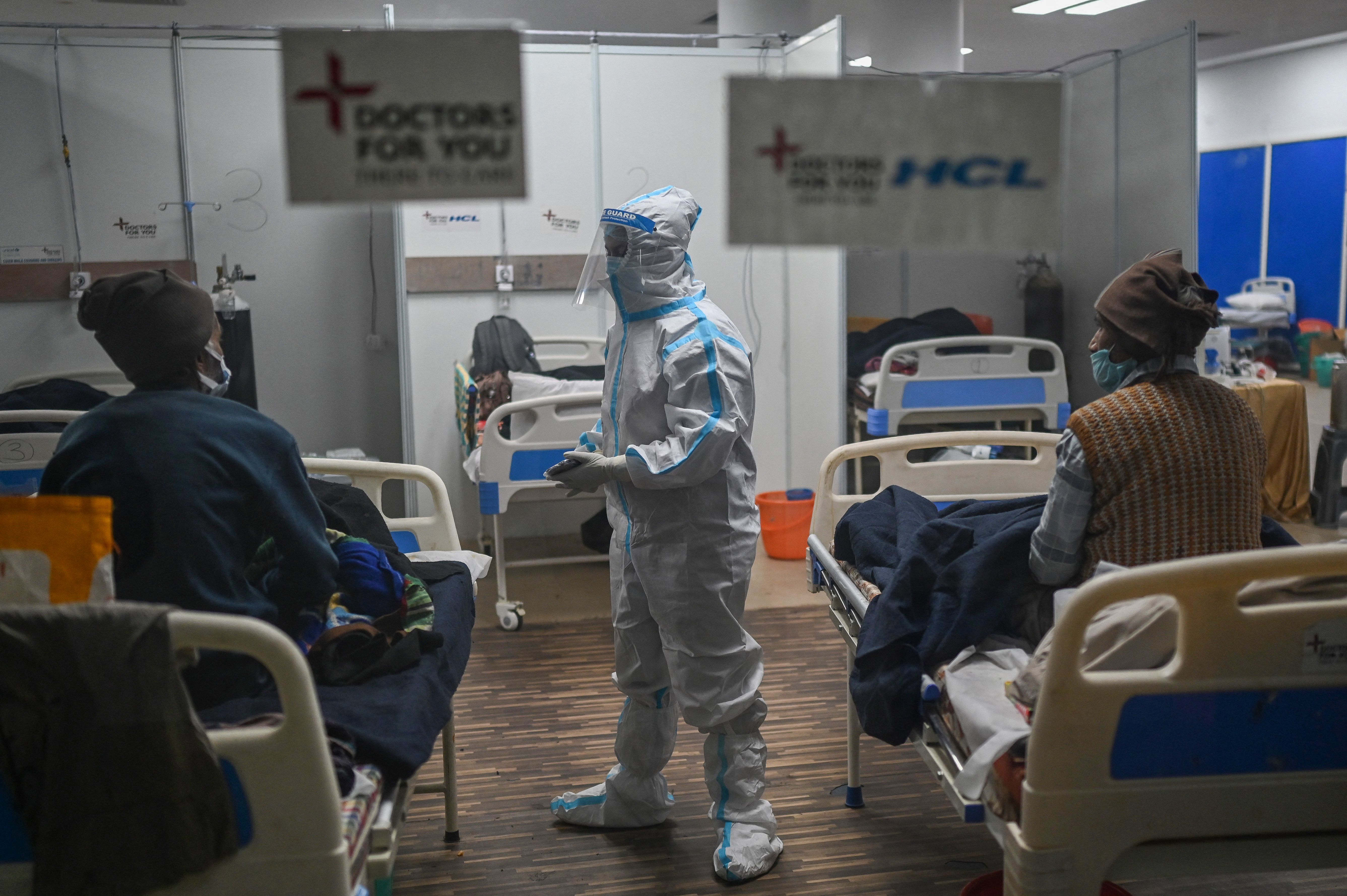 A health worker wearing Personal Protective Equipment (PPE) suit interacts with patients inside a ward at the Commonwealth games (CWG) village sports complex, temporarily converted into Covid-19 coronavirus care centre, in New Delhi on January 5, 2022. 