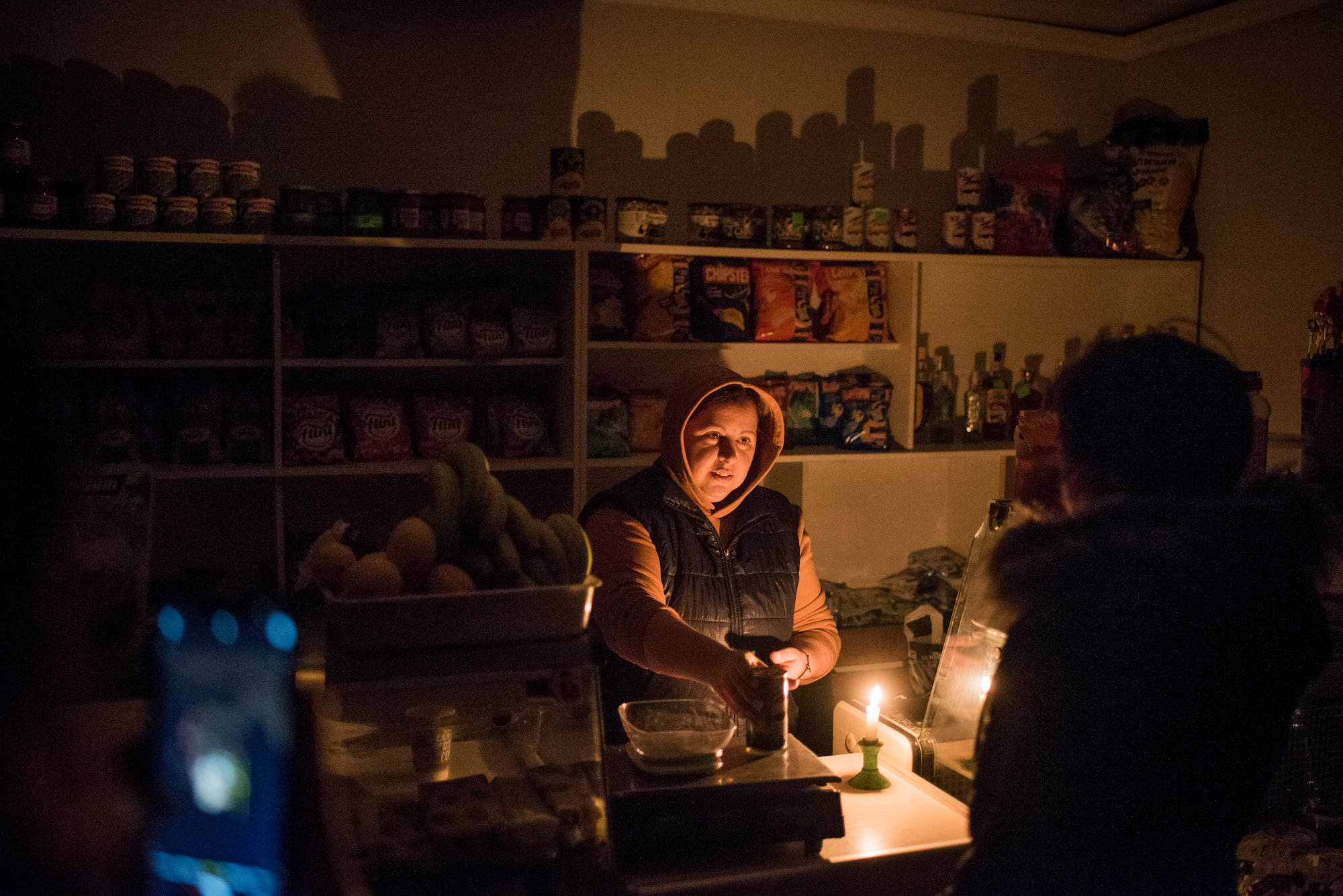 A shopkeeper works in a candle-lit store in the Odesa region on Thursday, during a 48-hour-long power blackout after Russian airstrikes.