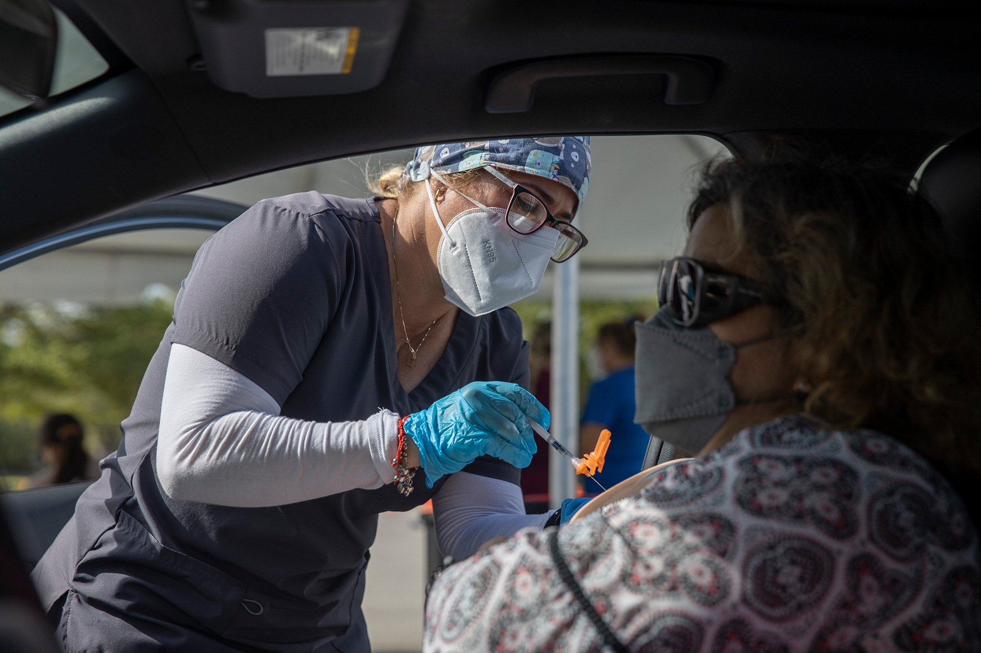 A healthcare worker administers a Pfizer-BioNTech COVID-19 vaccine to a person at a drive-thru site in Tropical Park on December 16, in Miami.