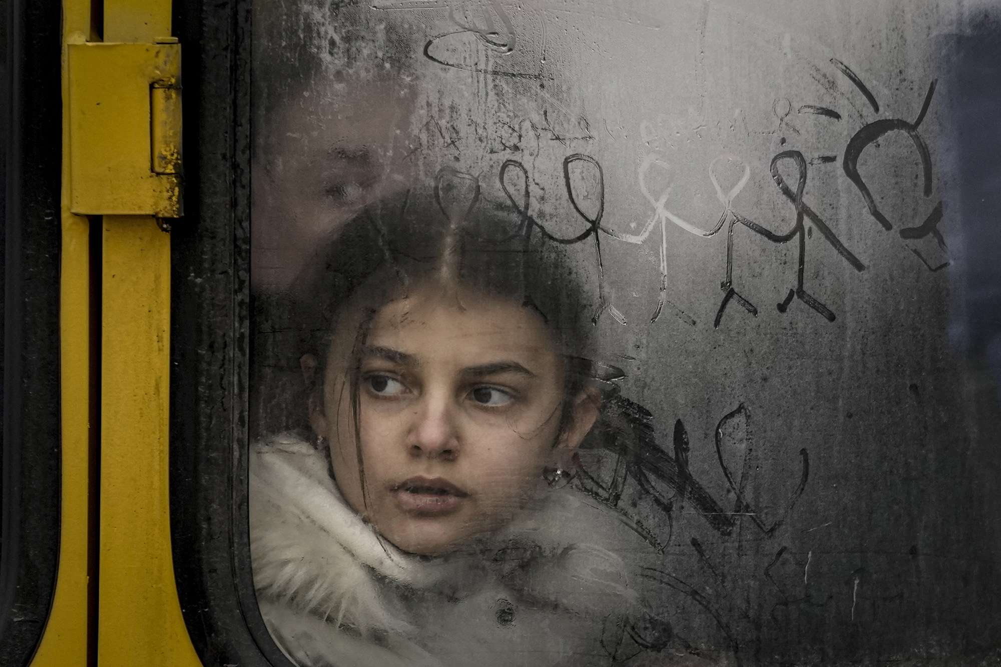 A child looks out a steamy bus window with finger-drawn doodles as civilians are evacuated from Irpin, on the outskirts of Kyiv, Ukraine, in this March 9, 2022 file photo. 
