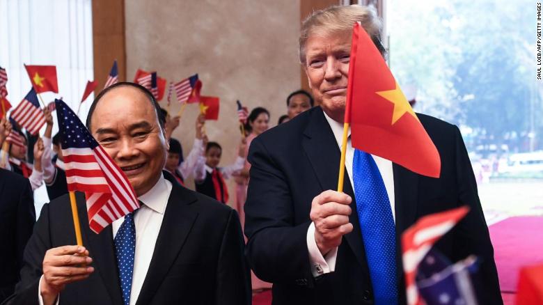Vietnamese Prime Minister Nguyen Xuan Phuc and US President Donald Trump wave flags ahead of a bilateral meeting in Hanoi, Vietnam. 