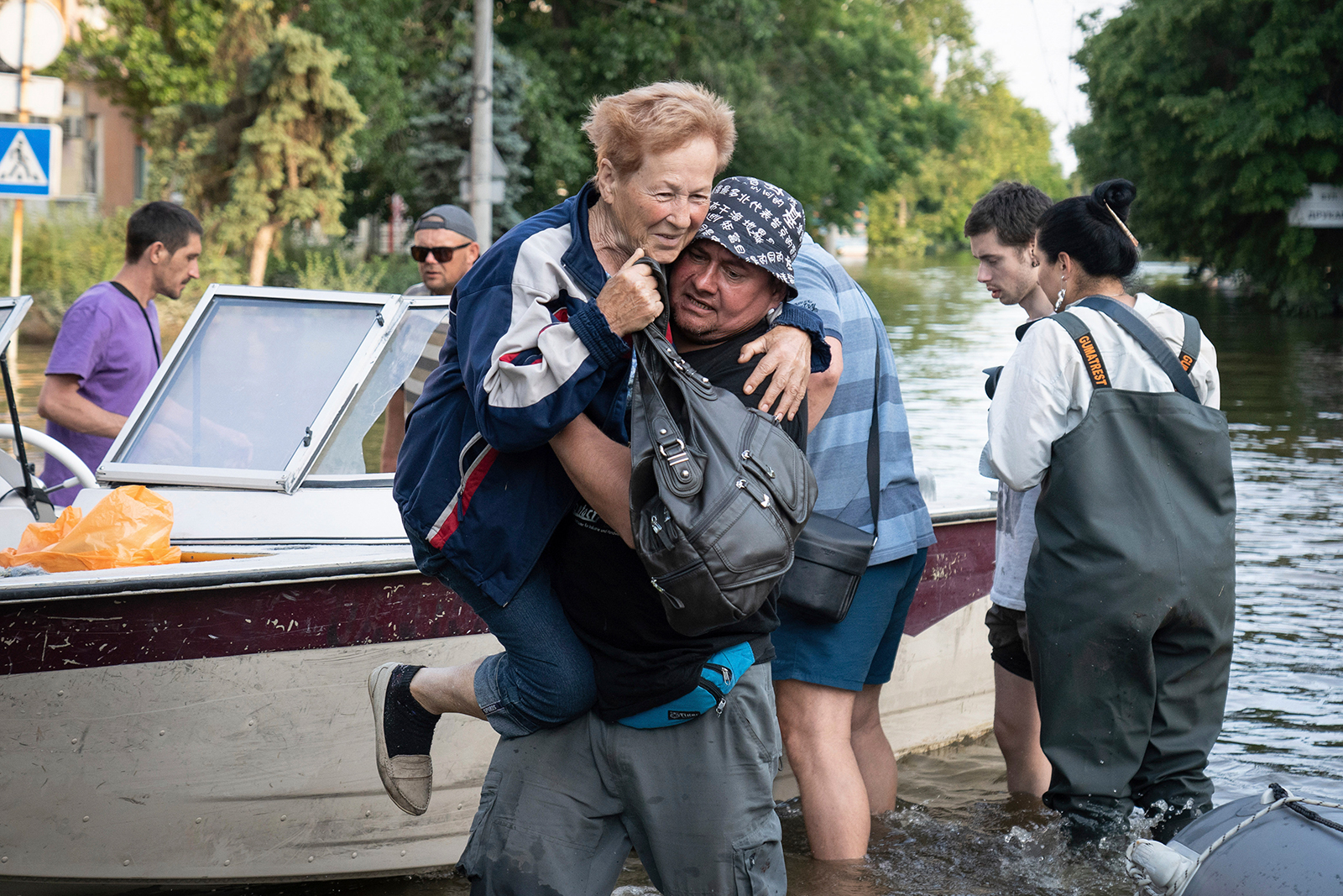 Se ve a un voluntario ucraniano flotando en el agua mientras lleva a una mujer desde un bote de evacuación en la ciudad de Kherson el 9 de junio.