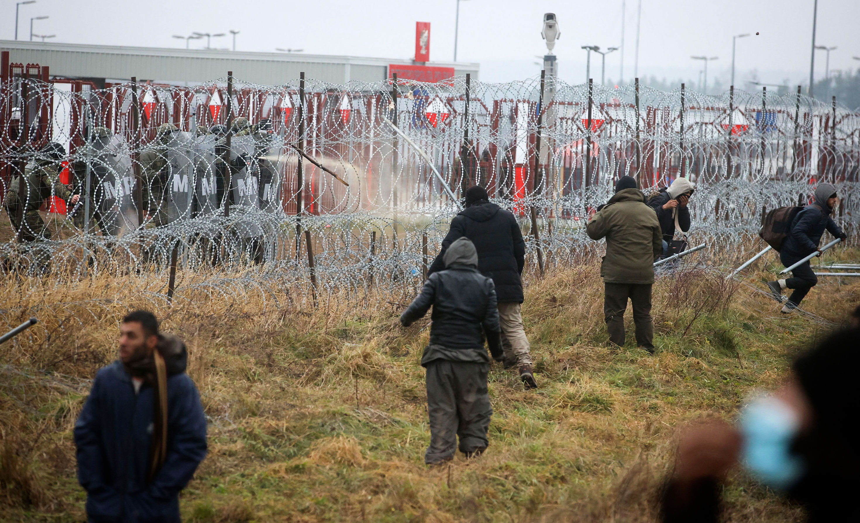 Polish servicemen, top left, spray tear gas during clashes between migrants and Polish border guards at the Belarus-Poland border near Grodno, Belarus, on November 16.