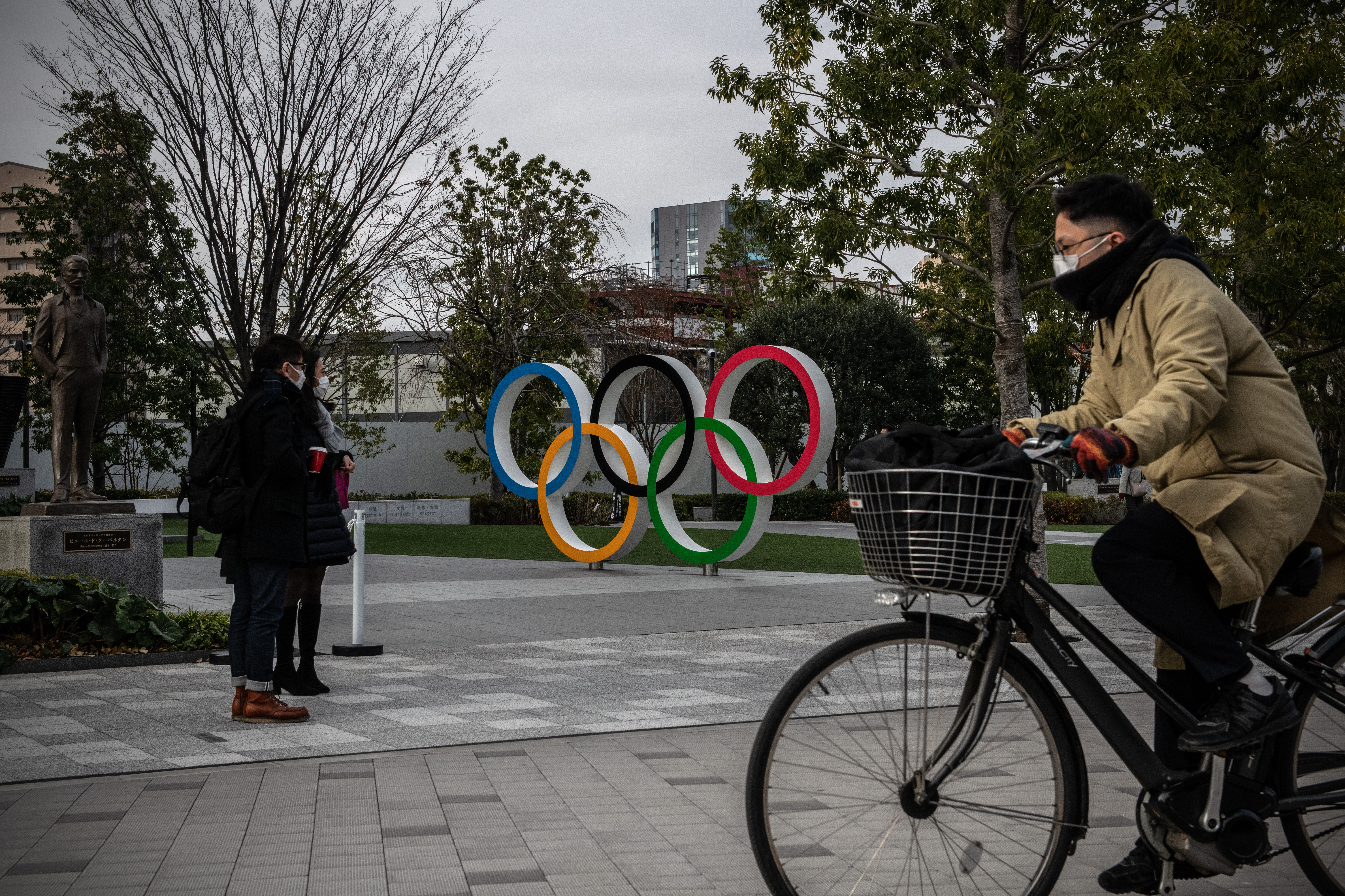 A man wearing a face mask cycles past the Olympic Rings on January 12 in Tokyo, Japan.