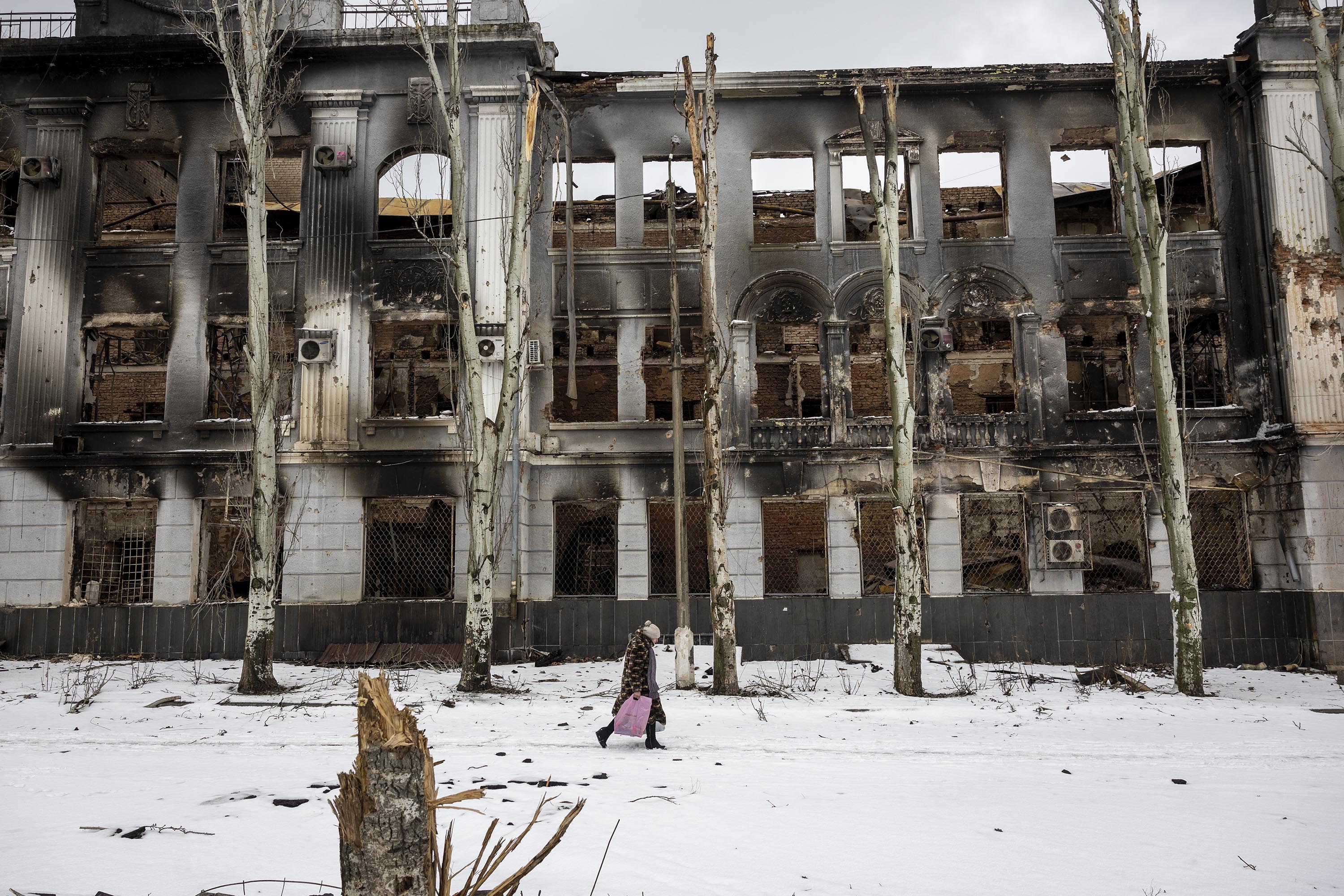 A local resident carries humanitarian aid while passing through a battle-scarred downtown area of Bakhmut, Ukraine, on February 14. 